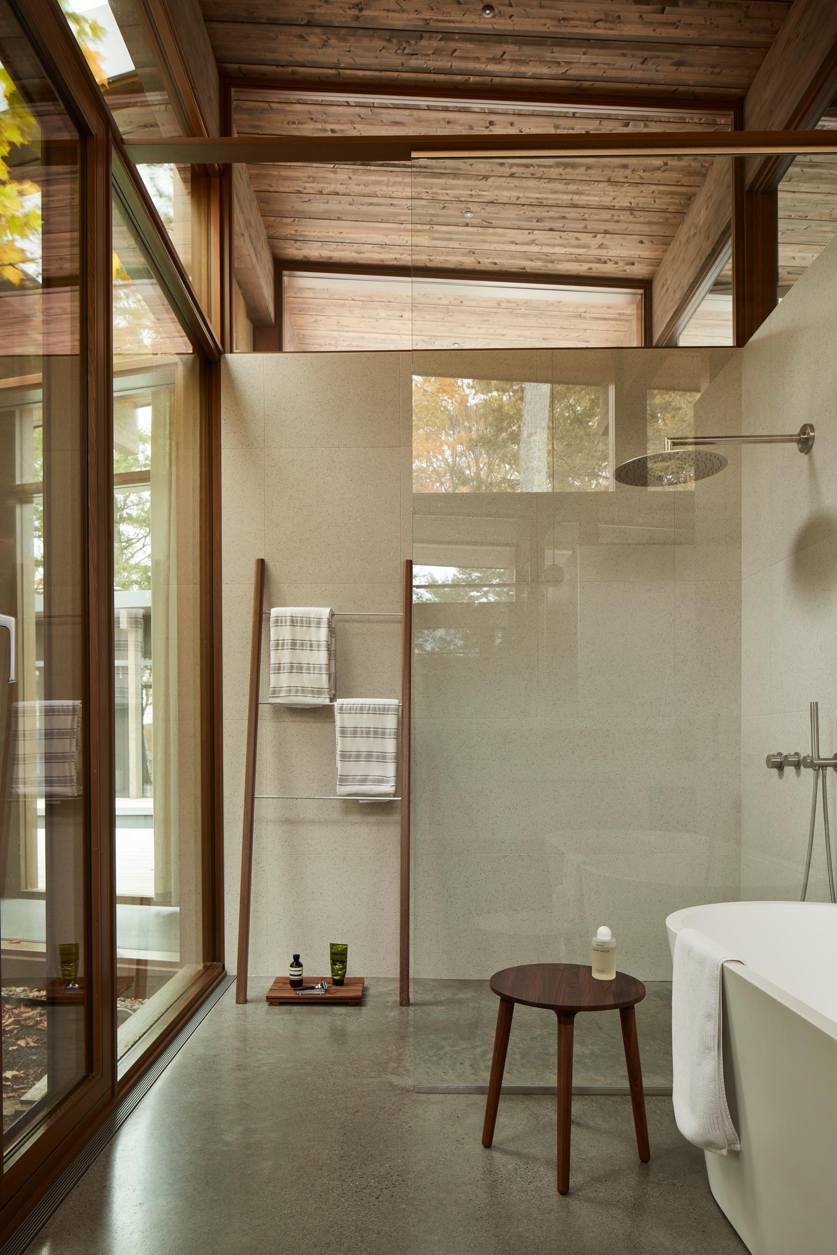 In this minimalist bathroom, wood accents have been added in the form of a decorative ladder, tray, and stool.