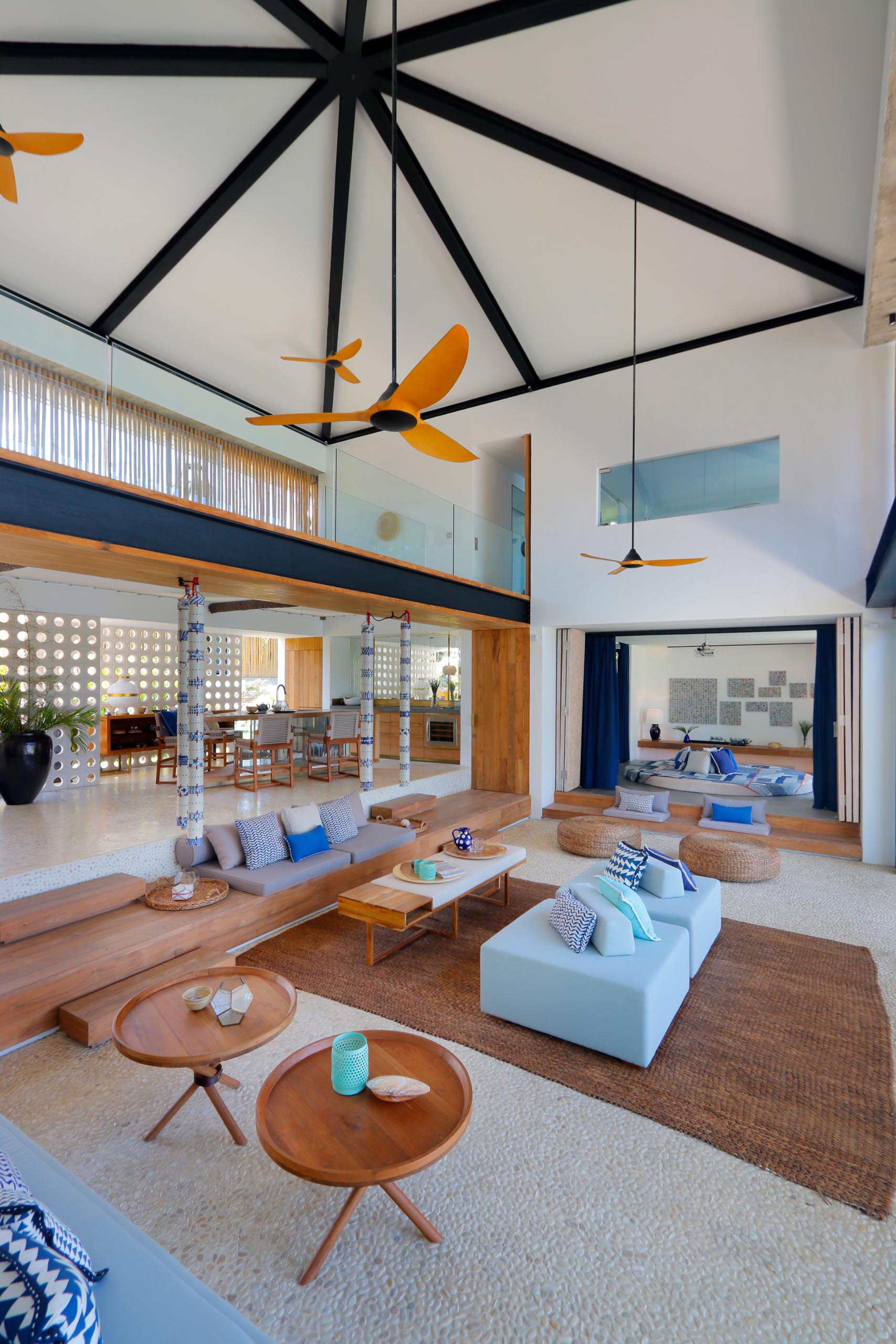 A modern beach house interior with an open living room and double height ceiling.