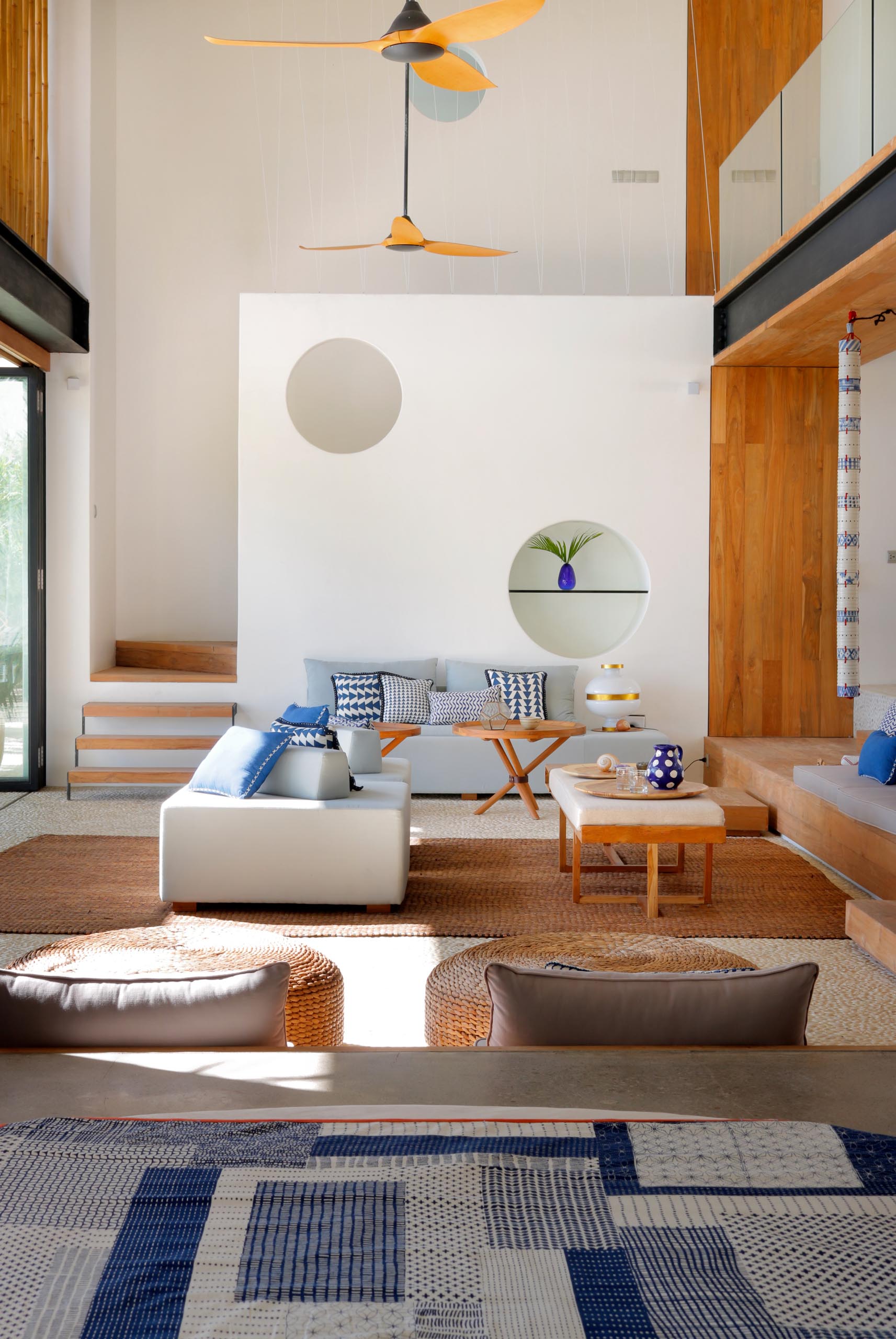 A modern beach house interior with an open living room and double height ceiling.