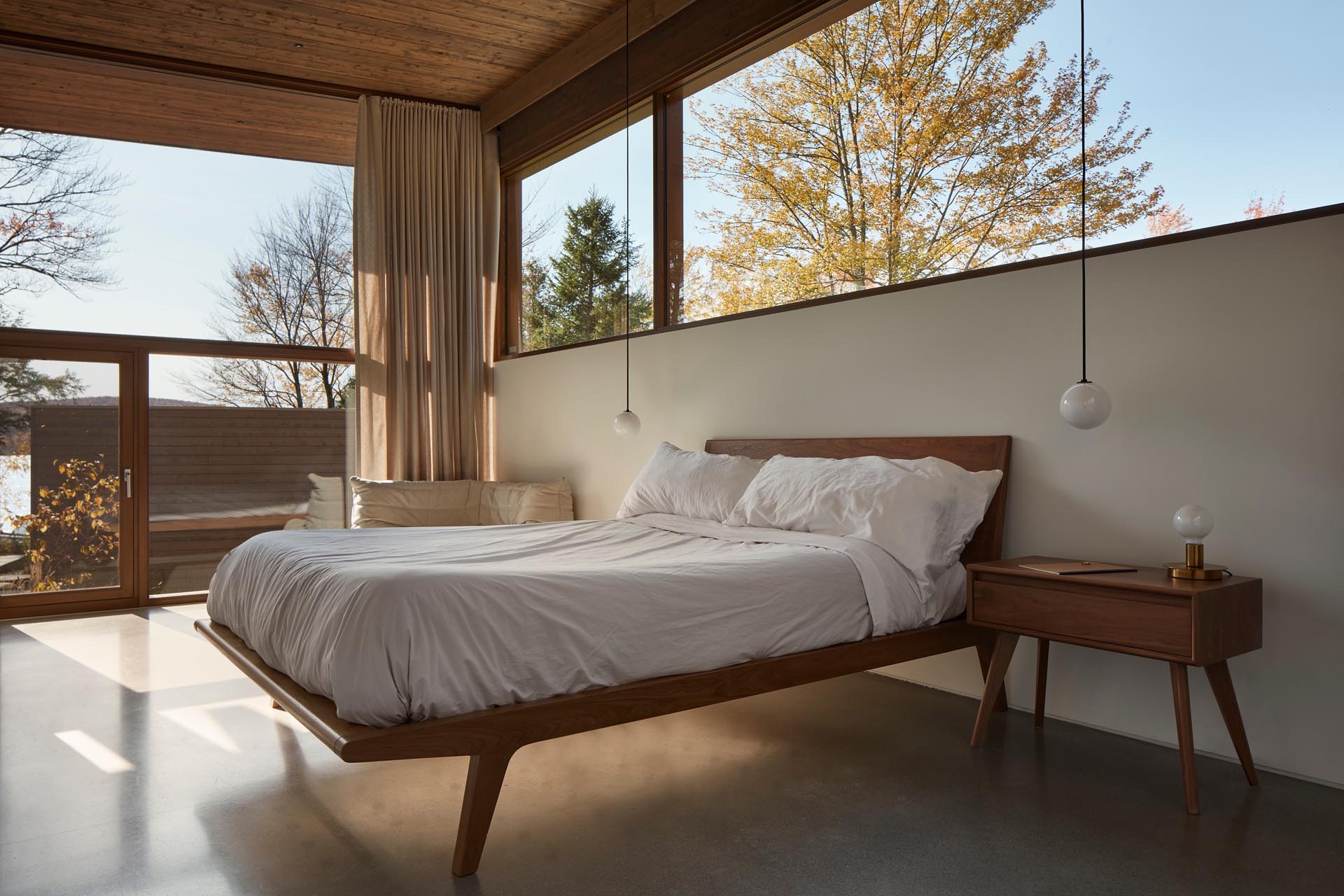 A modern bedroom with a concrete floor and a wood bed frame with matching side tables.