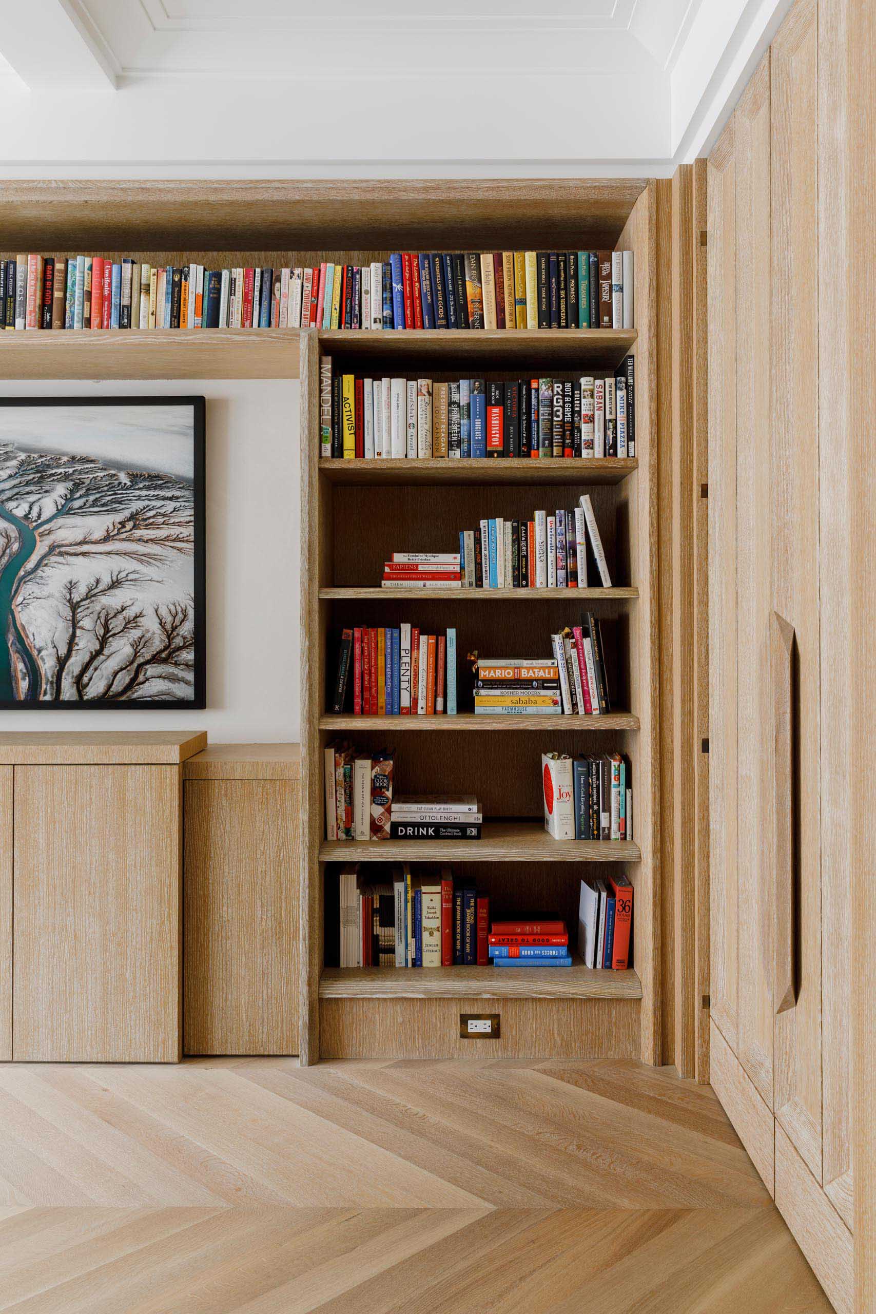 Custom bookshelves and white oak floors in a chevron pattern.