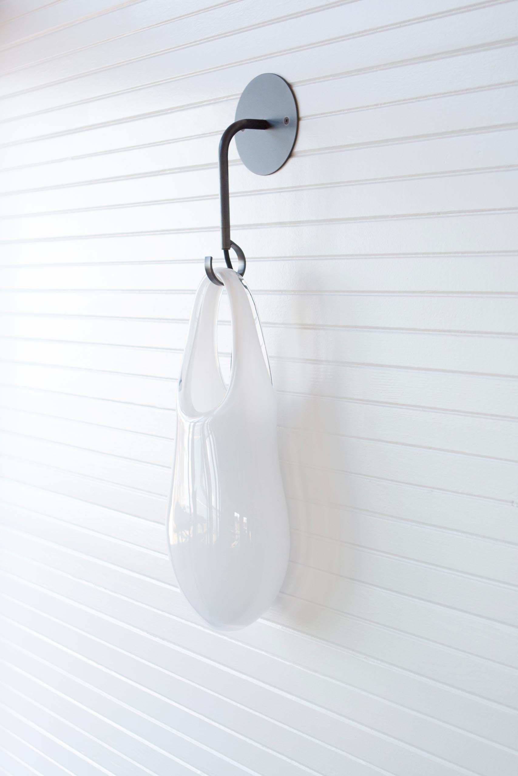 The Hold pendant lights and sconces, are modern handblown glass lights that look like they're hanging from hooks.