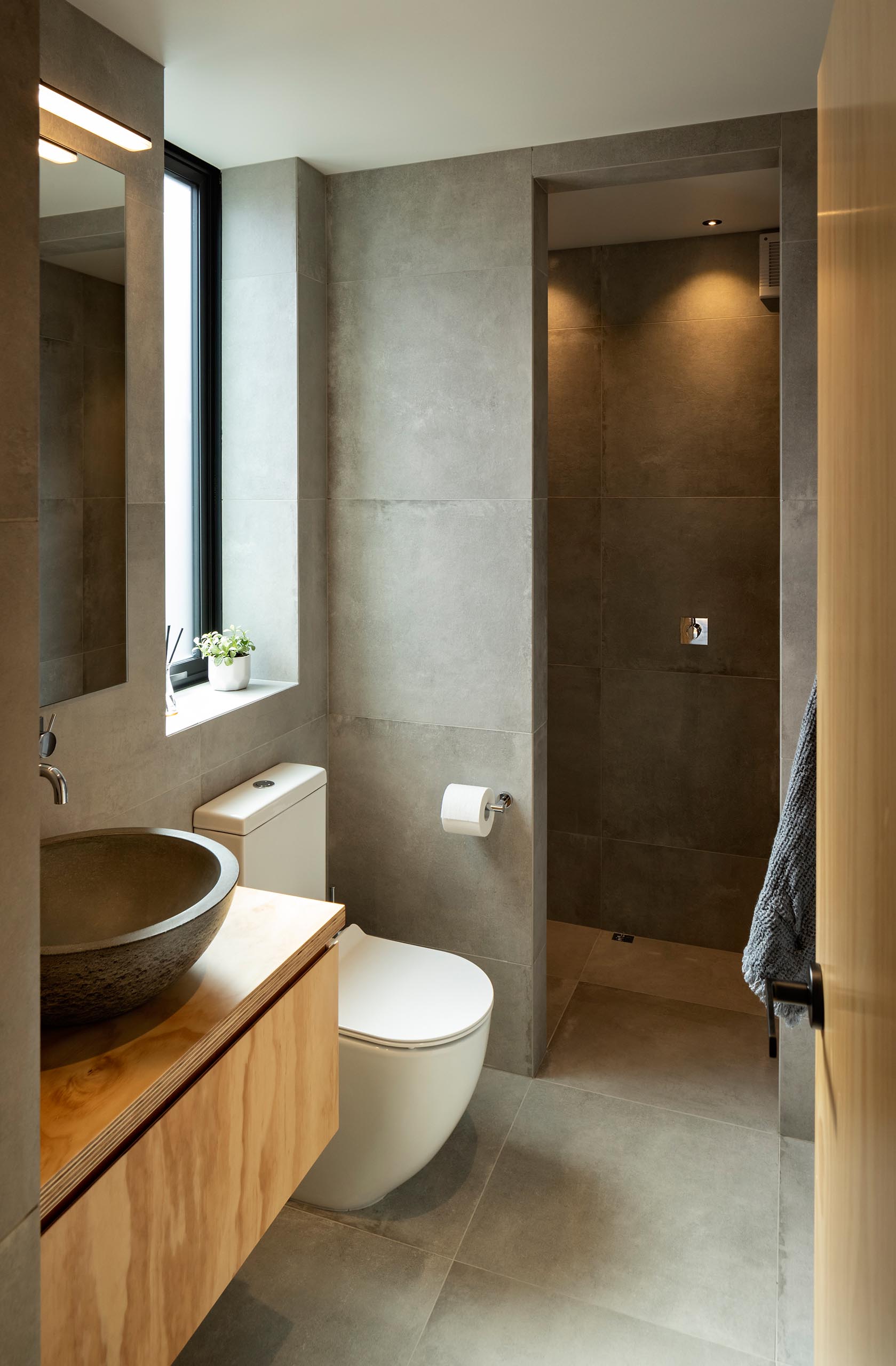 A modern bathroom reminiscent of a Japanese spa with floor to ceiling, stone-look tiles.
