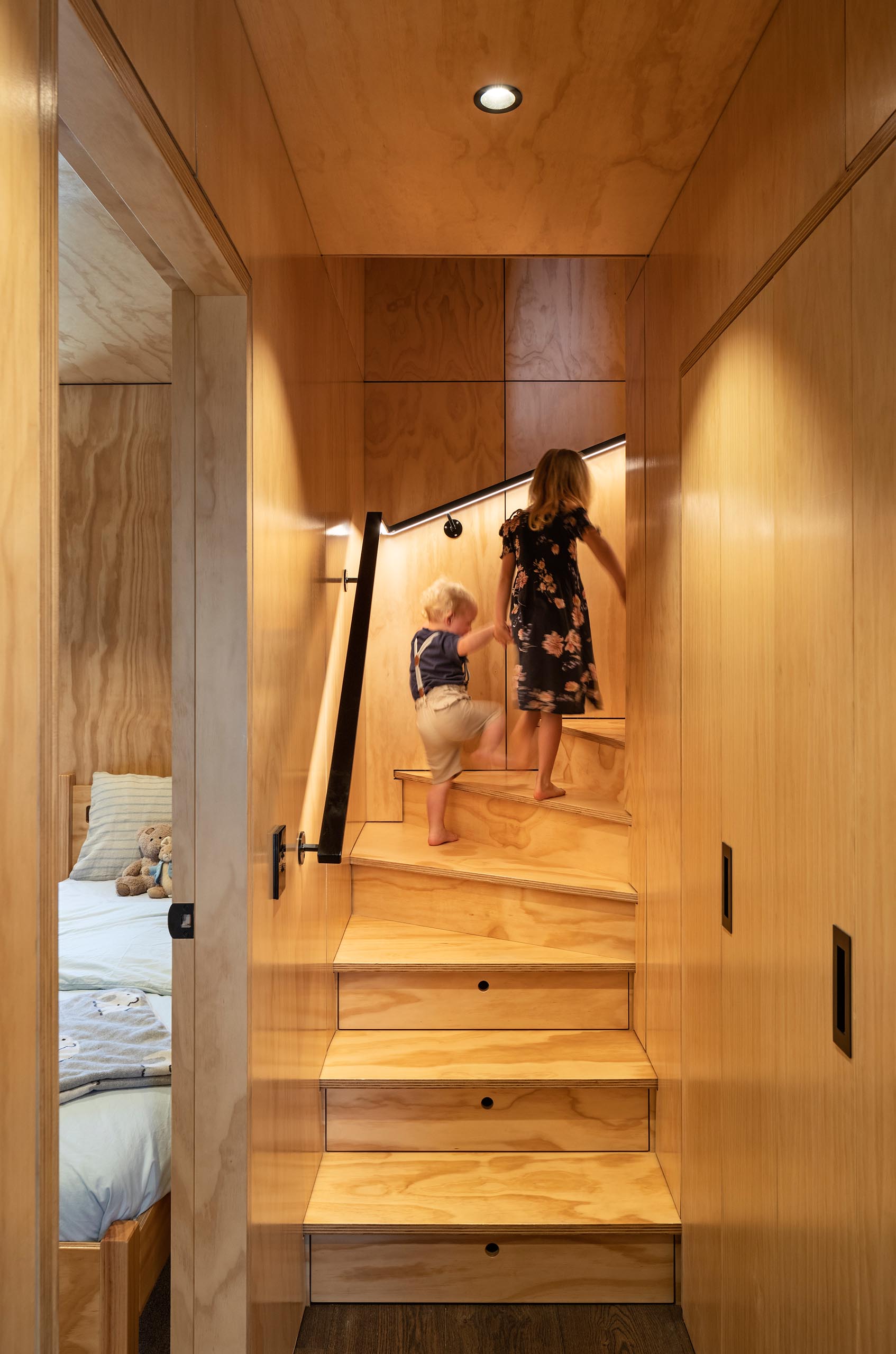 Wood stairs lead to the upper floor of the home, while a black handrail has hidden lighting to guide the way.