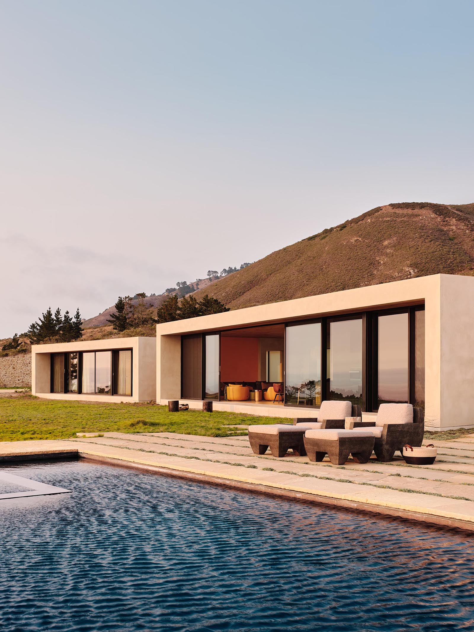 Sliding glass walls line the walls facing the ocean, and connect the interiors of this modern house to the outdoor spaces and the swimming pool.