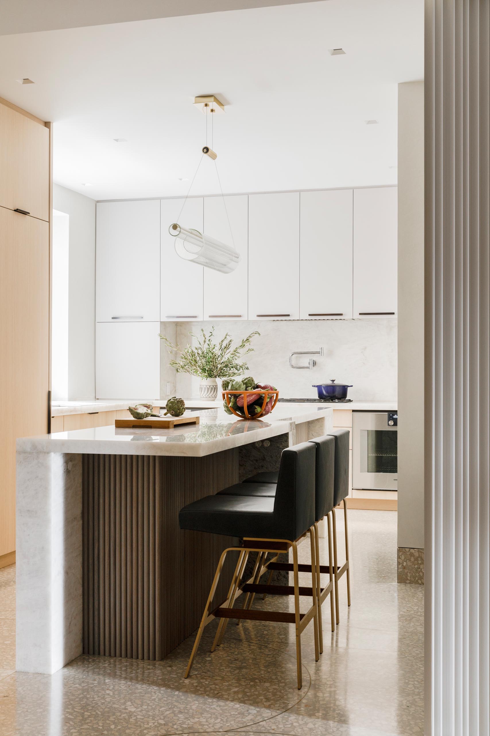 This kitchen Island is Henrybuilt with hefty stone legs and ribbed walnut cladding designed by MKCA, while the countertops are a mix of Cristallo and Ice Grey marble.
