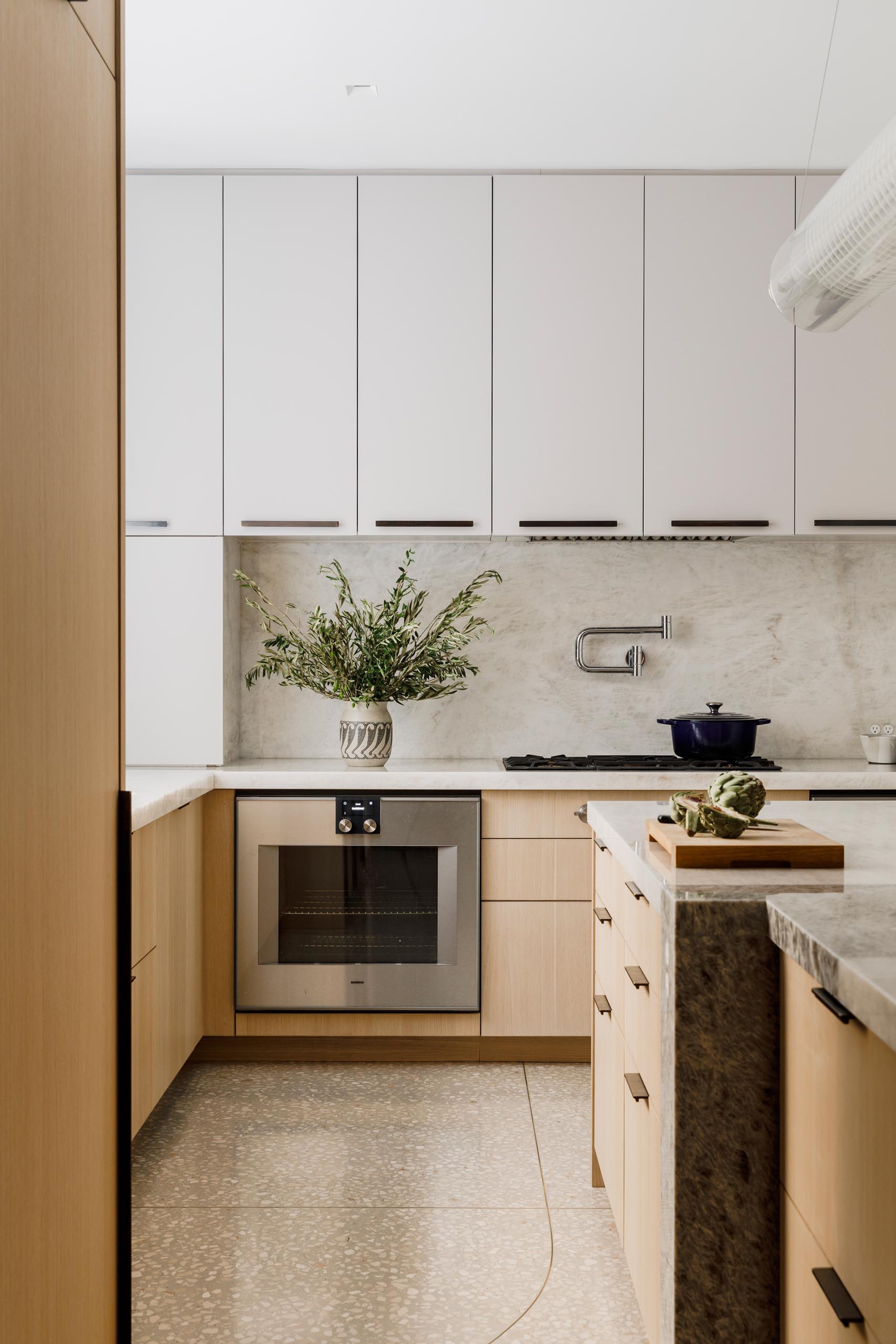 Within this modern kitchen there's cabinetry designed is by Henrybuilt, with additional customization by MKCA. The countertops are white Cristallo quartz and the floor is terrazzo.