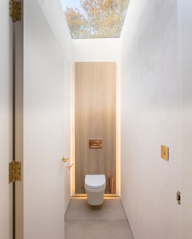 A small powder room with a wood accent wall and a skylight.