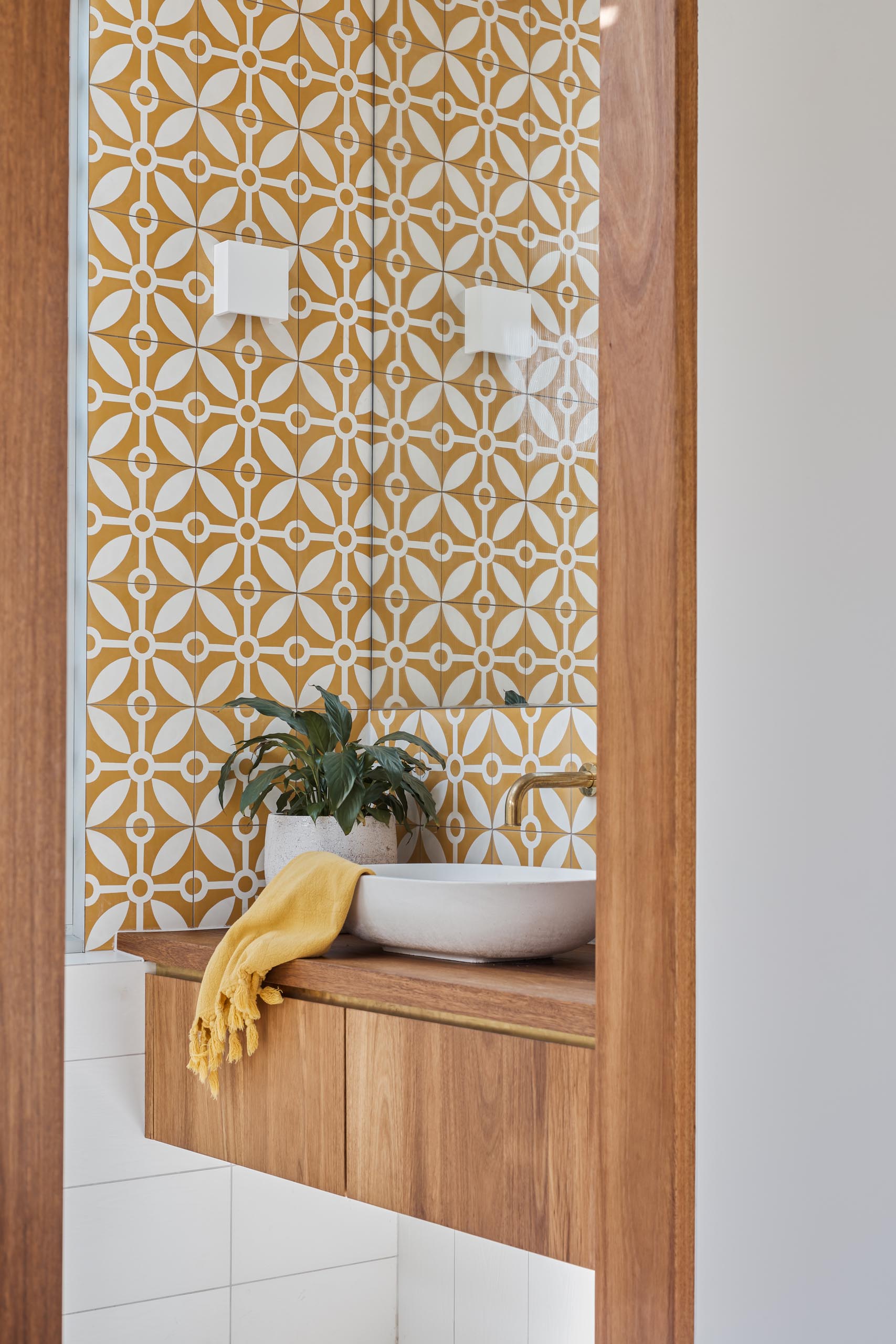 This modern en-suite bathroom includes patterned tiles, a warm wood vanity, and a walk-in shower.