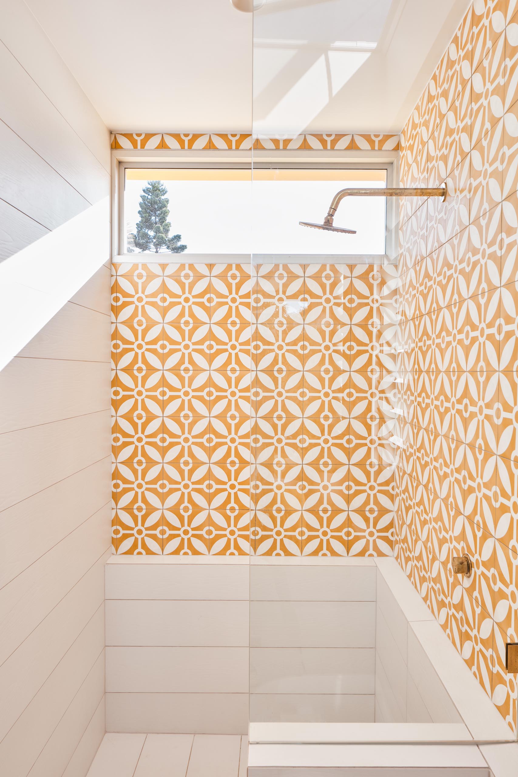 This modern en-suite bathroom includes patterned tiles, a warm wood vanity, and a walk-in shower.