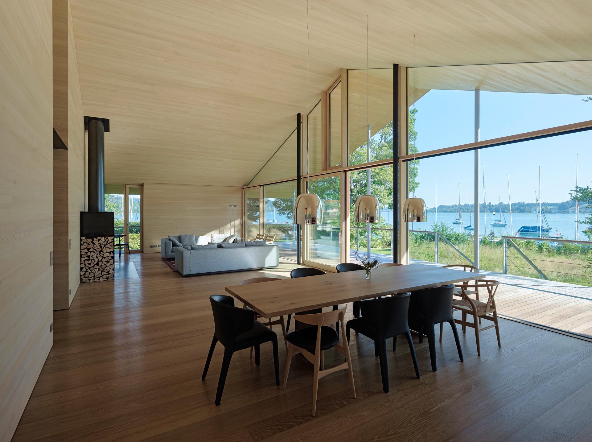 An open plan living room and dining room showcases a full wall of windows that look out to the lake and boats.