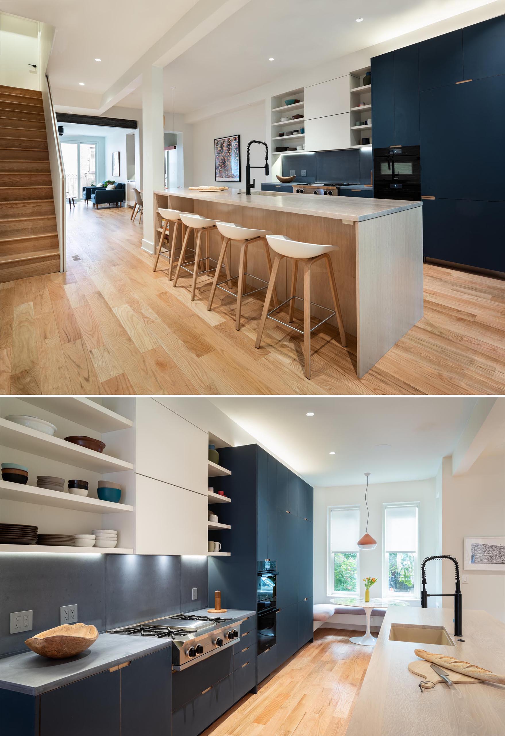 This modern kitchen includes blue and white cabinets, gray countertops and backsplash, and a wood island with seating.