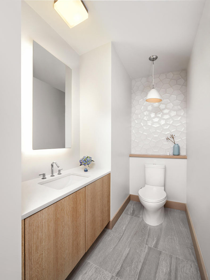 A small bathroom with accents of textured tile and wood.