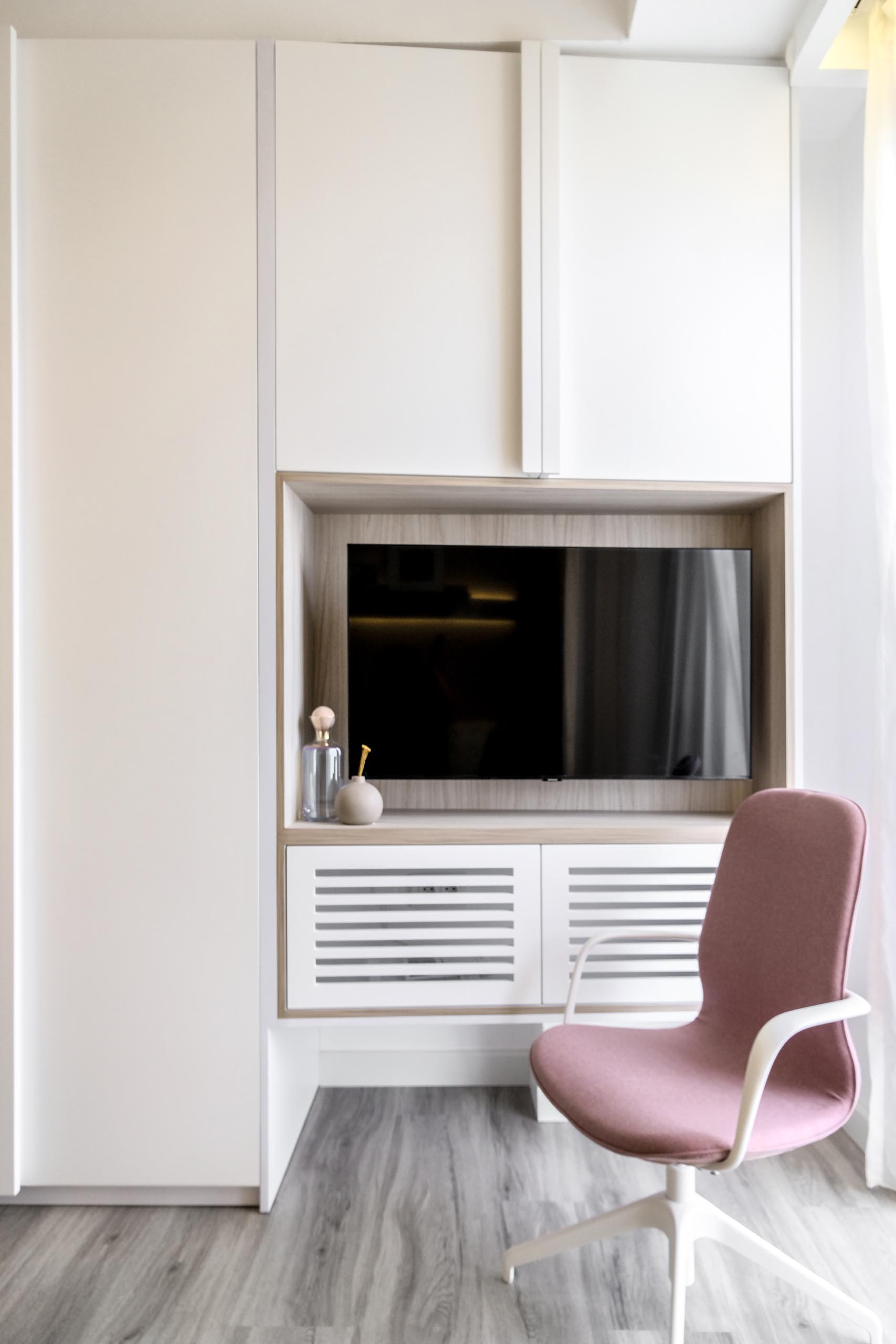 A small apartment with a niche for a television, is surrounded by cabinets, adding storage to the small apartment.