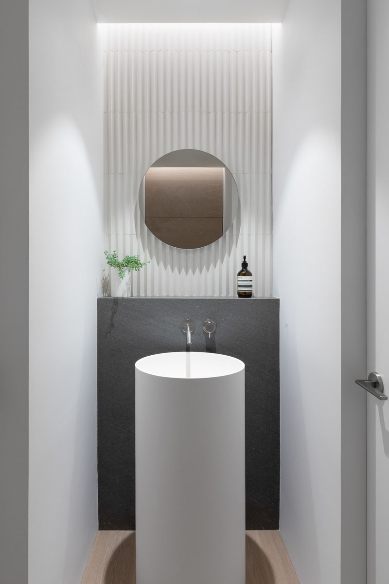 A powder room in a small house designed by Falken Reynolds Interiors and Randy Bens Architect, includes a pedestal sink and faucet, a Basalt ledge, and Mutina tile on the wall.