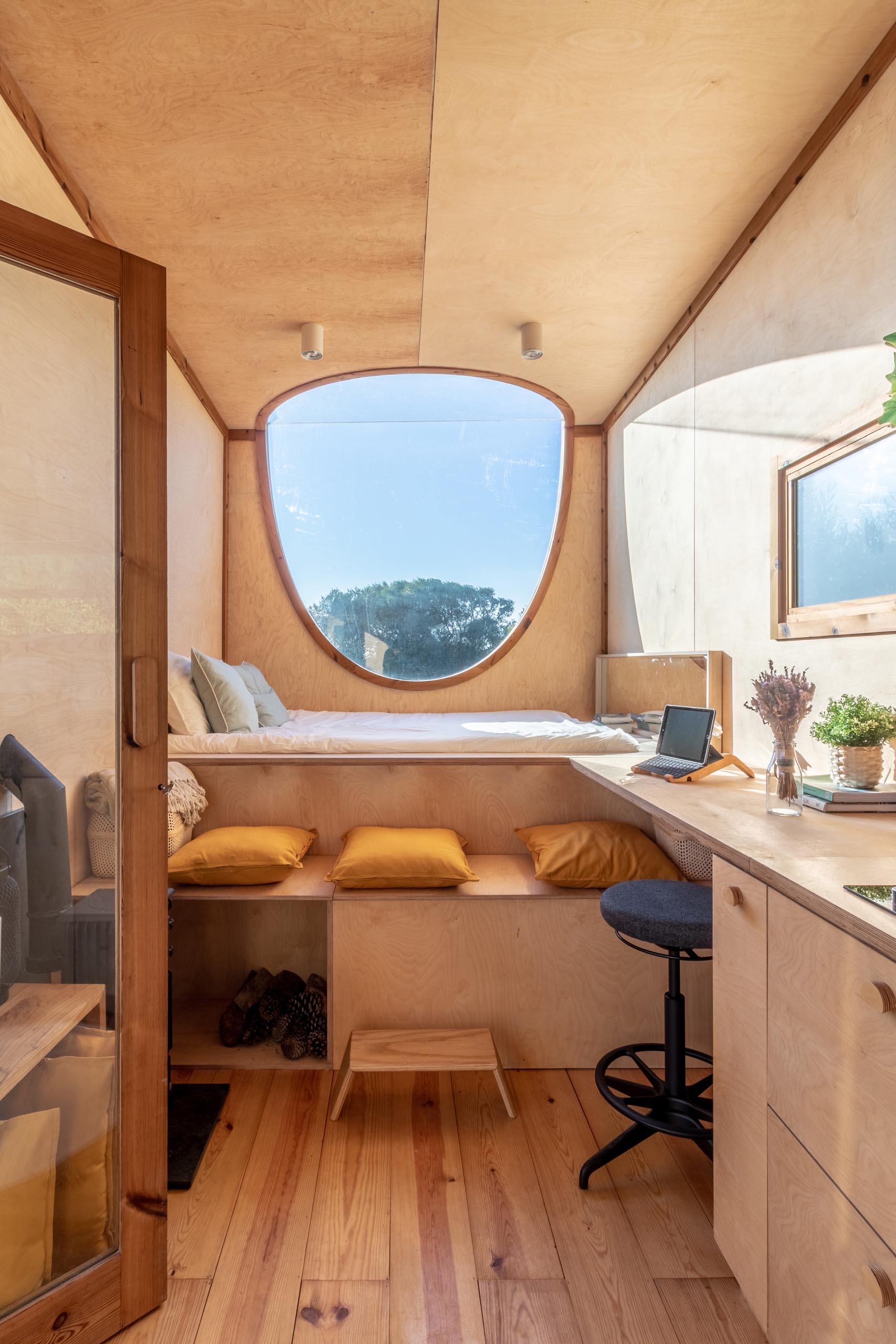 The oval-shaped window in this modern tiny house allows you to have views of the sky whether you're laying in bed or sitting up.
