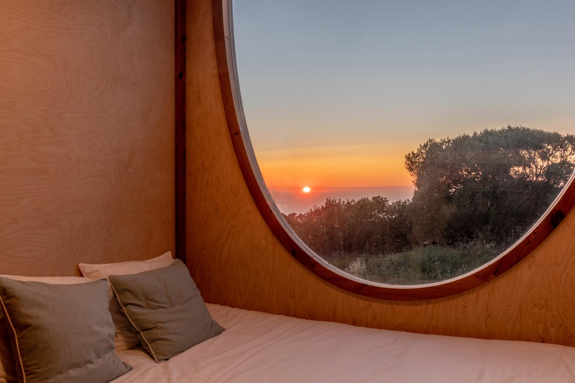 A tiny house with an oval mirror by the bed.