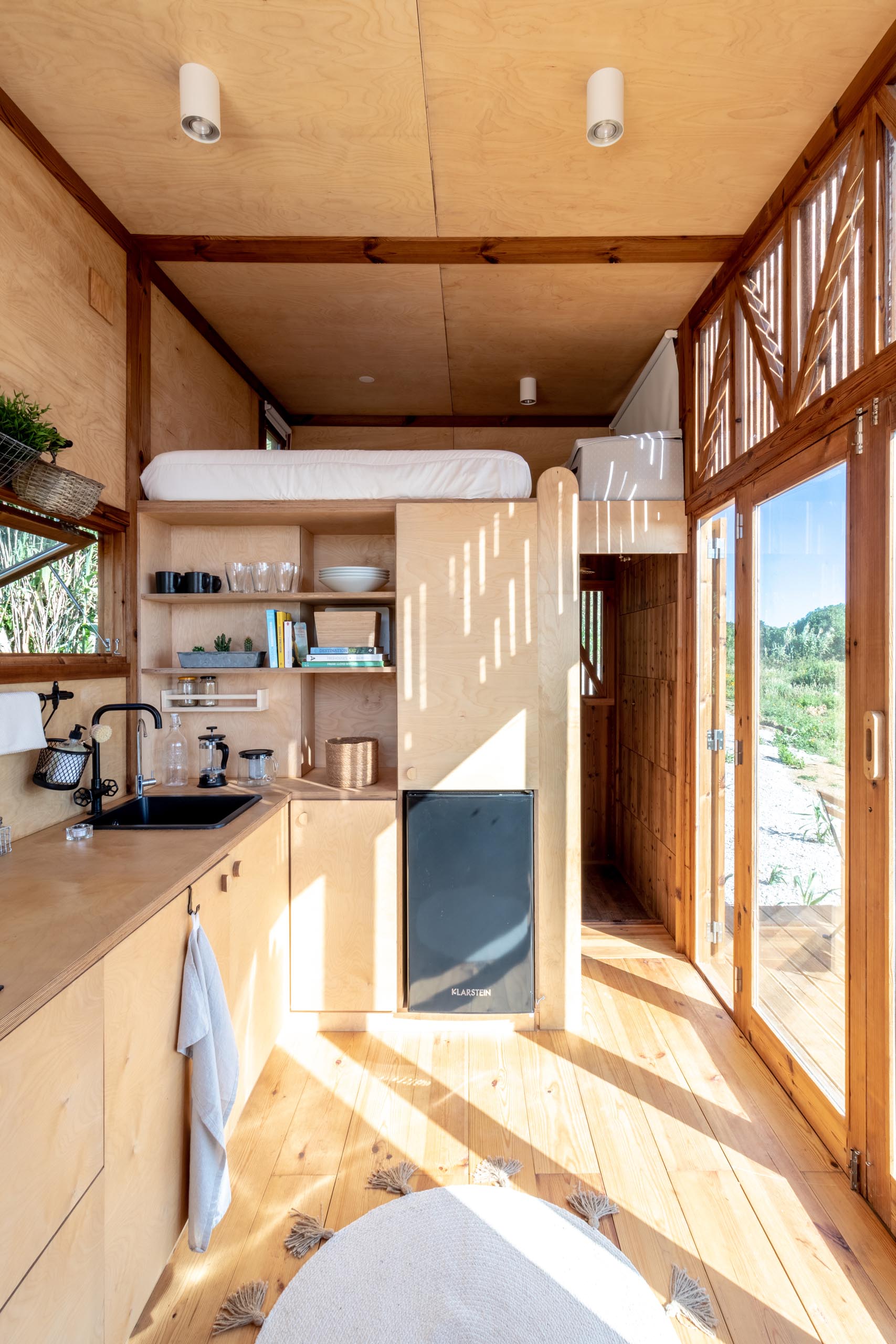 This modern tiny house has a sleeping loft located above the bathroom.