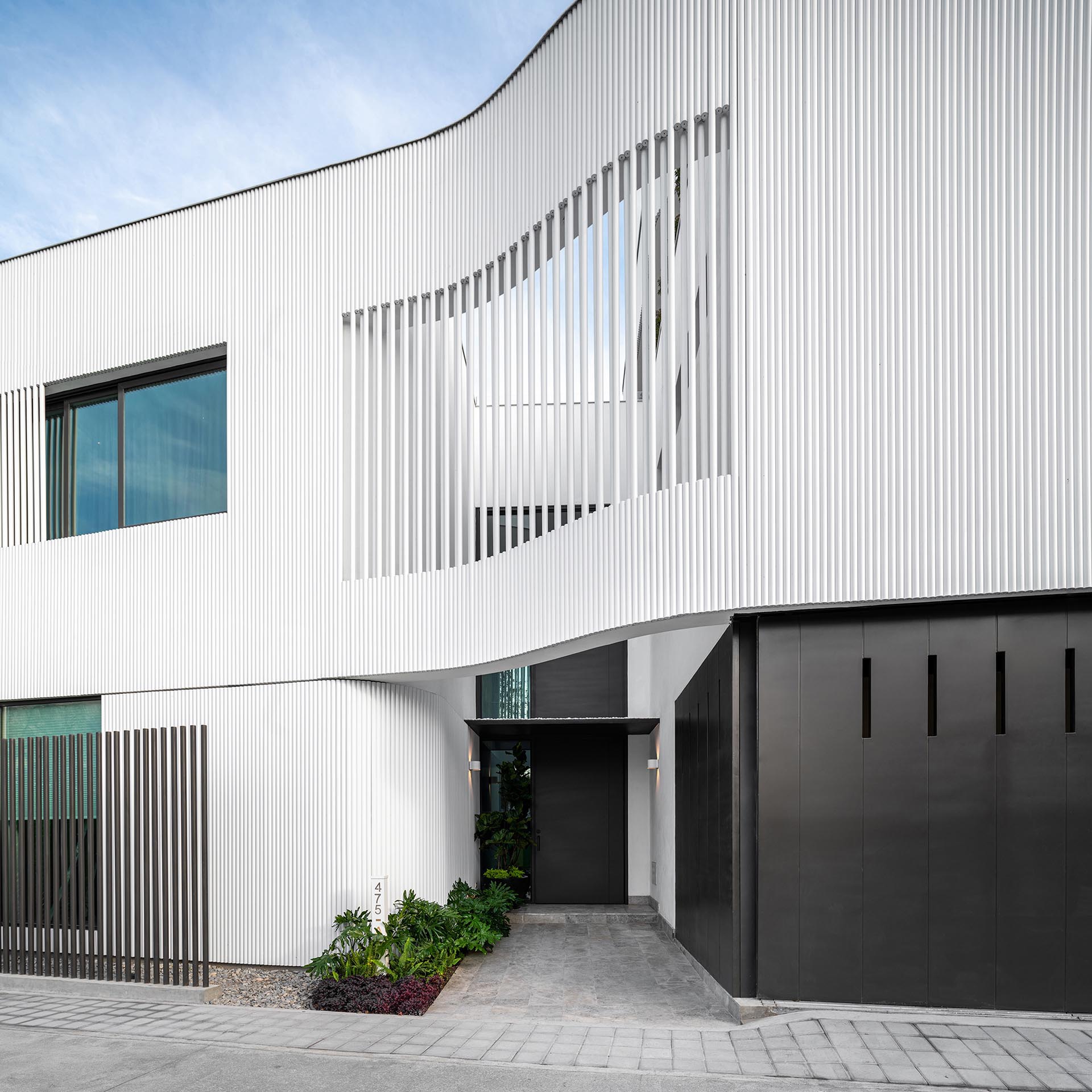 The metal pipes create a screen on the exterior of this modern house, and serve as a rainscreen for the solid walls, act as privacy and shading for selected windows