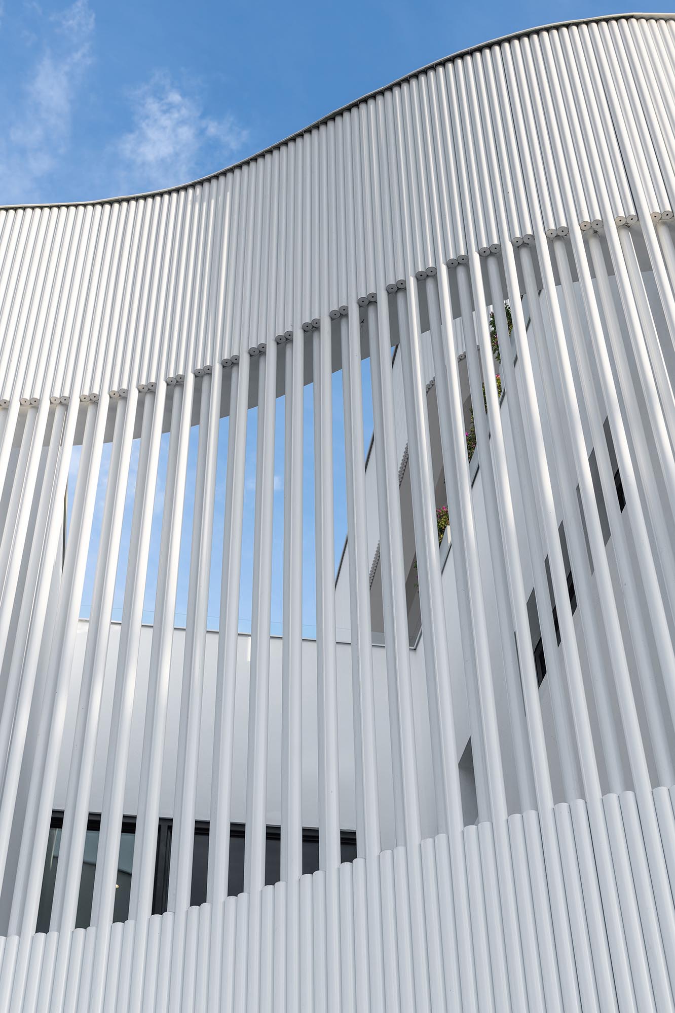 The metal pipes create a screen on the exterior of this modern house, and serve as a rainscreen for the solid walls, act as privacy and shading for selected windows