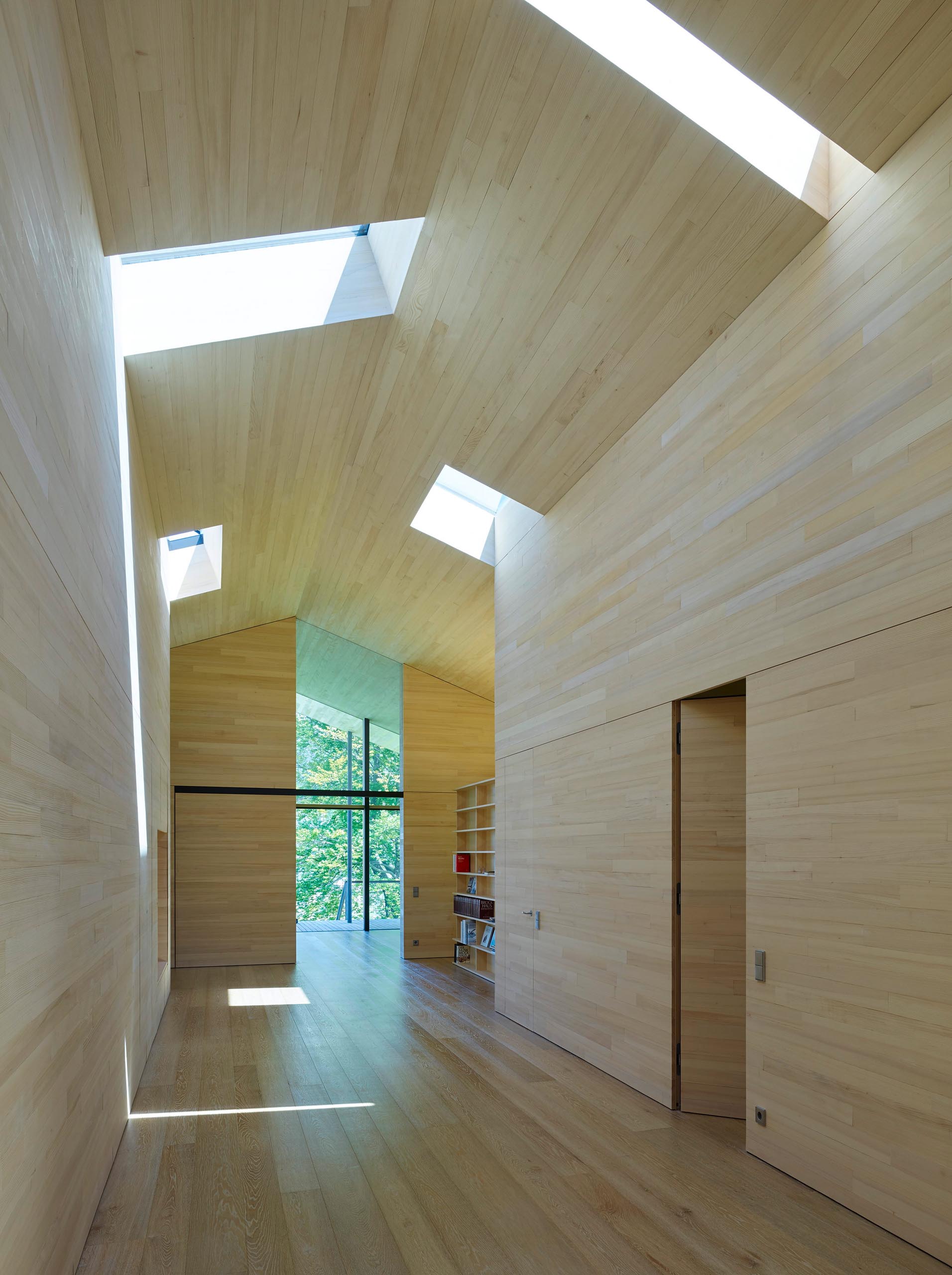 Inside this home, wood lines the walls, floor, and ceiling, while skylights brighten the hallway leading from the door to the social areas. 