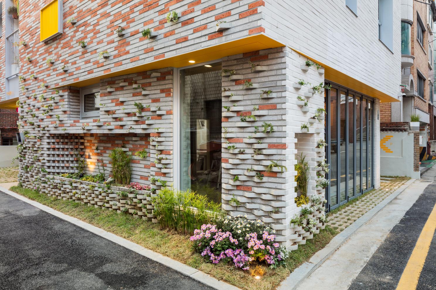 A modern brick building with incorporated plants into the facade.