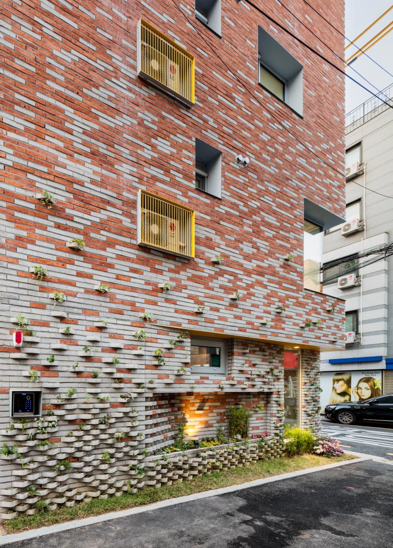 A modern brick building with incorporated plants into the facade.