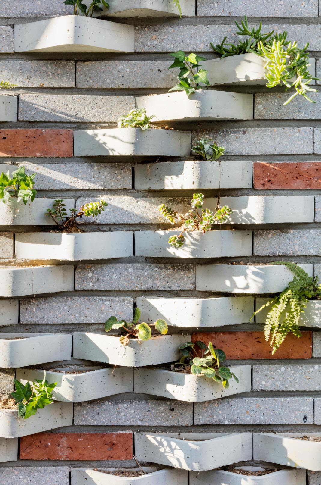 A modern brick building with incorporated plants into the facade.