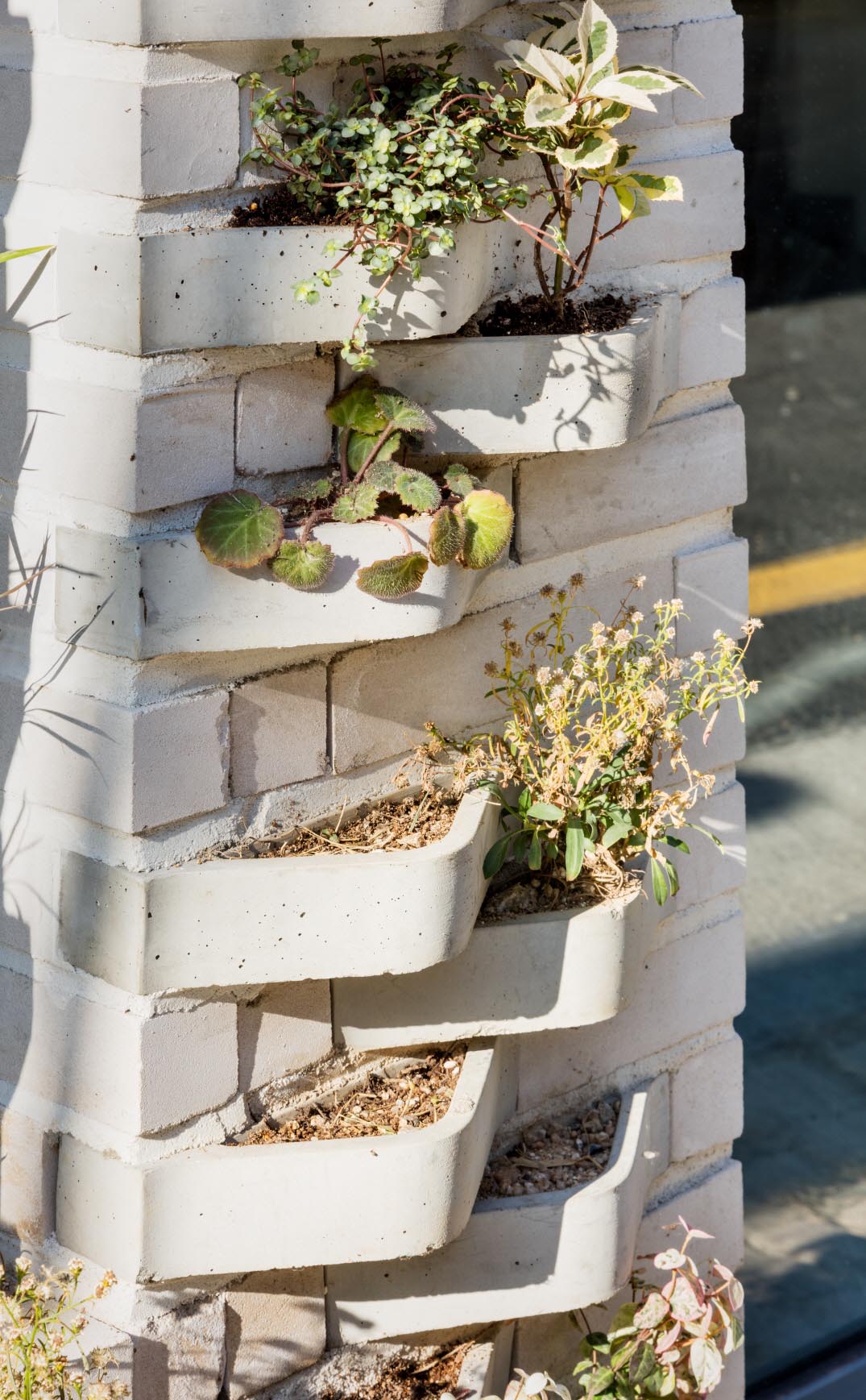 A modern brick building with incorporated plants into the facade.