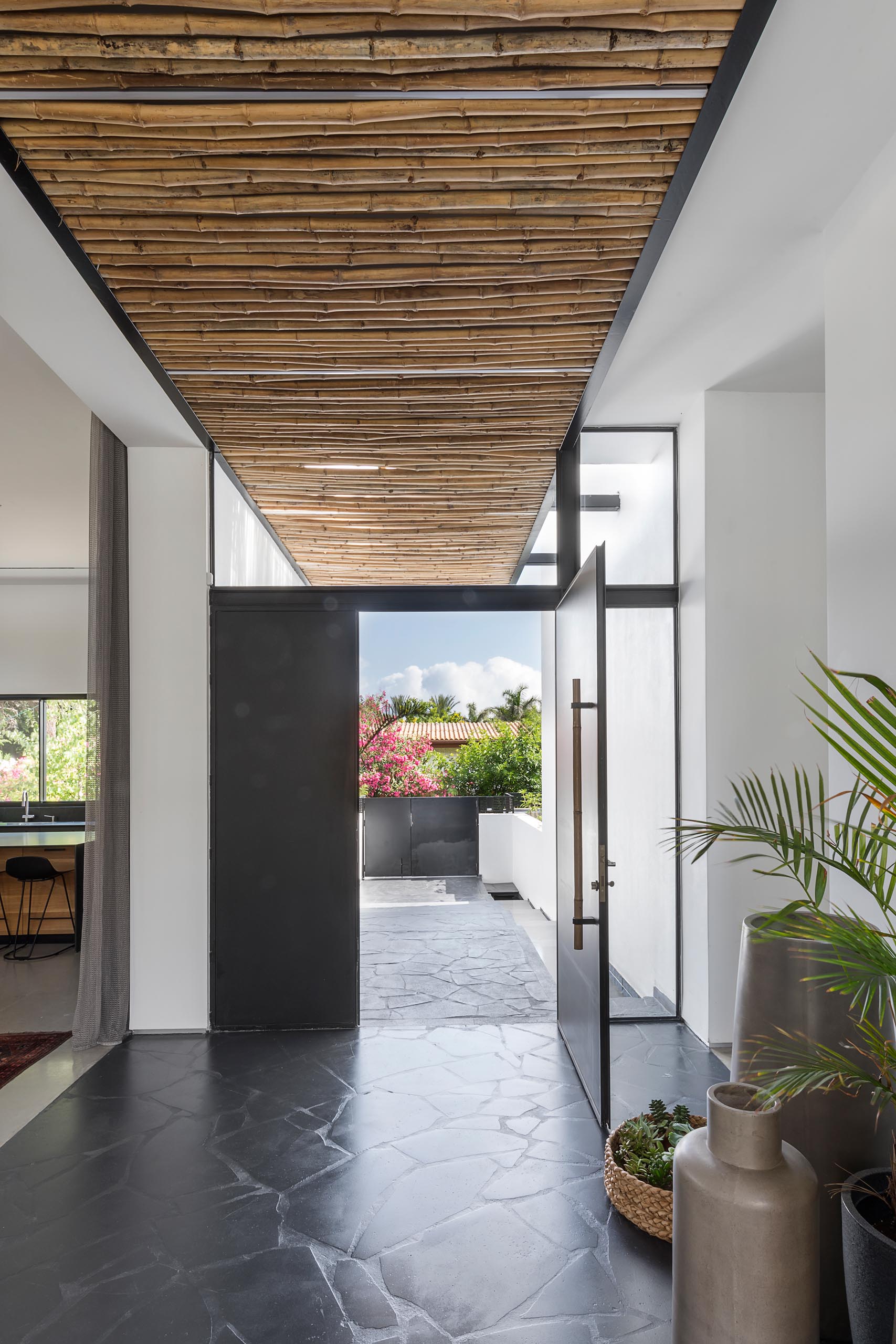 This modern bamboo screens act as a rain cover for the black front door, and flow through to the interior of the home, and then onto the backyard.