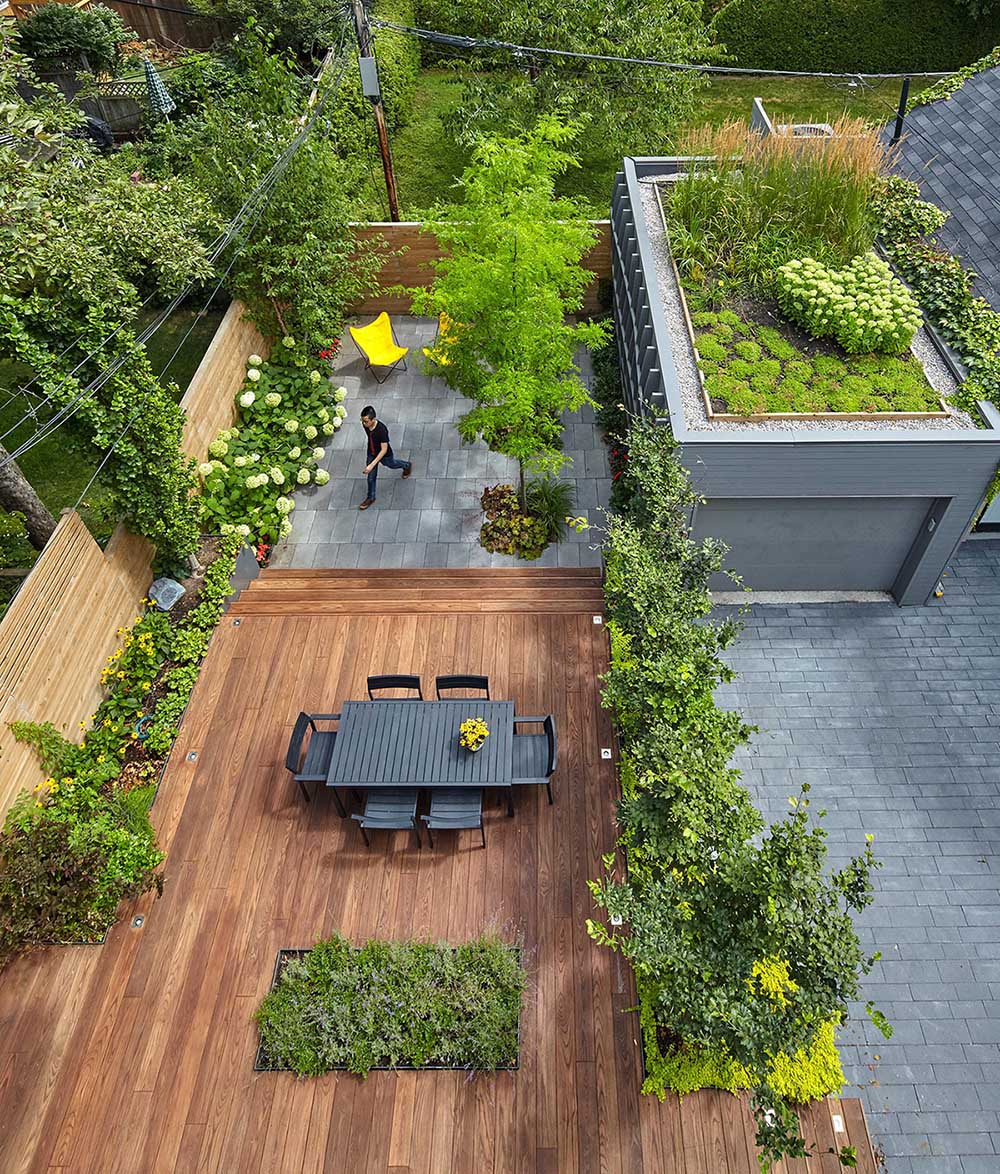 The rear yard is landscaped and features a generously scaled thermally treated ash wood deck, and a few steps down, another zone defined by granite pavers is planted with a row of honey locust trees that offer dappled light and shade in summer. There's also a small garage with green roof.