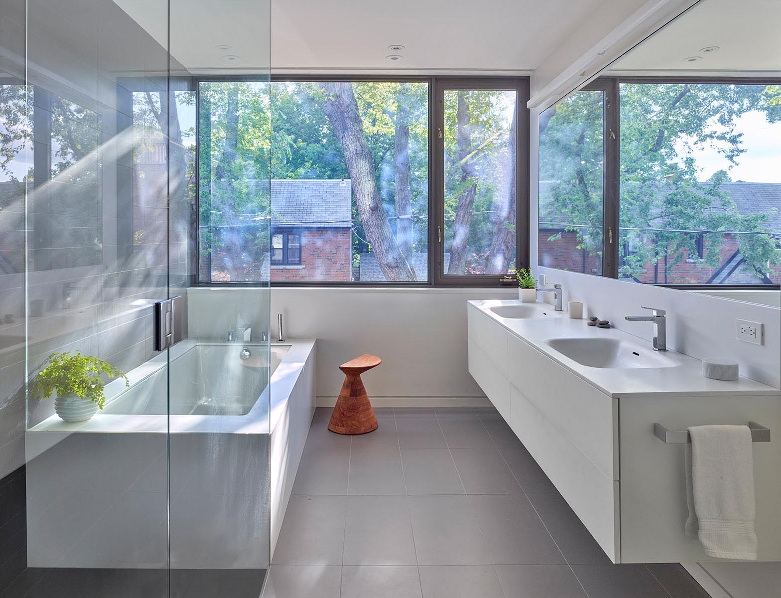 In this modern bathroom, a floating white vanity lines the wall, while the opposite wall is home to a built-in bathtub and a glass enclosed shower.