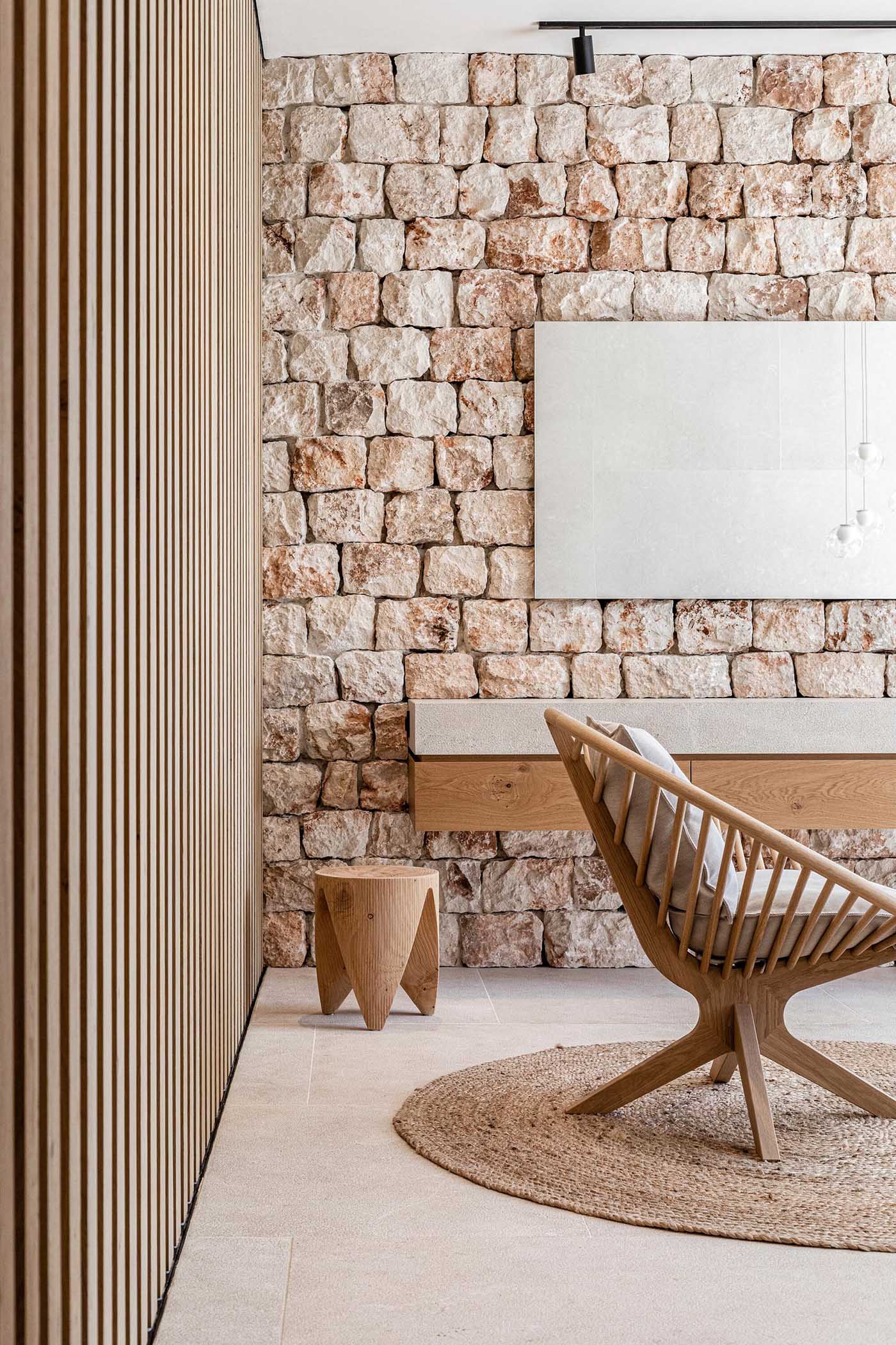 In this modern bathroom, the stone wall becomes a backdrop for the floating vanity, while a freestanding bathtub is perfectly positioned for water views.