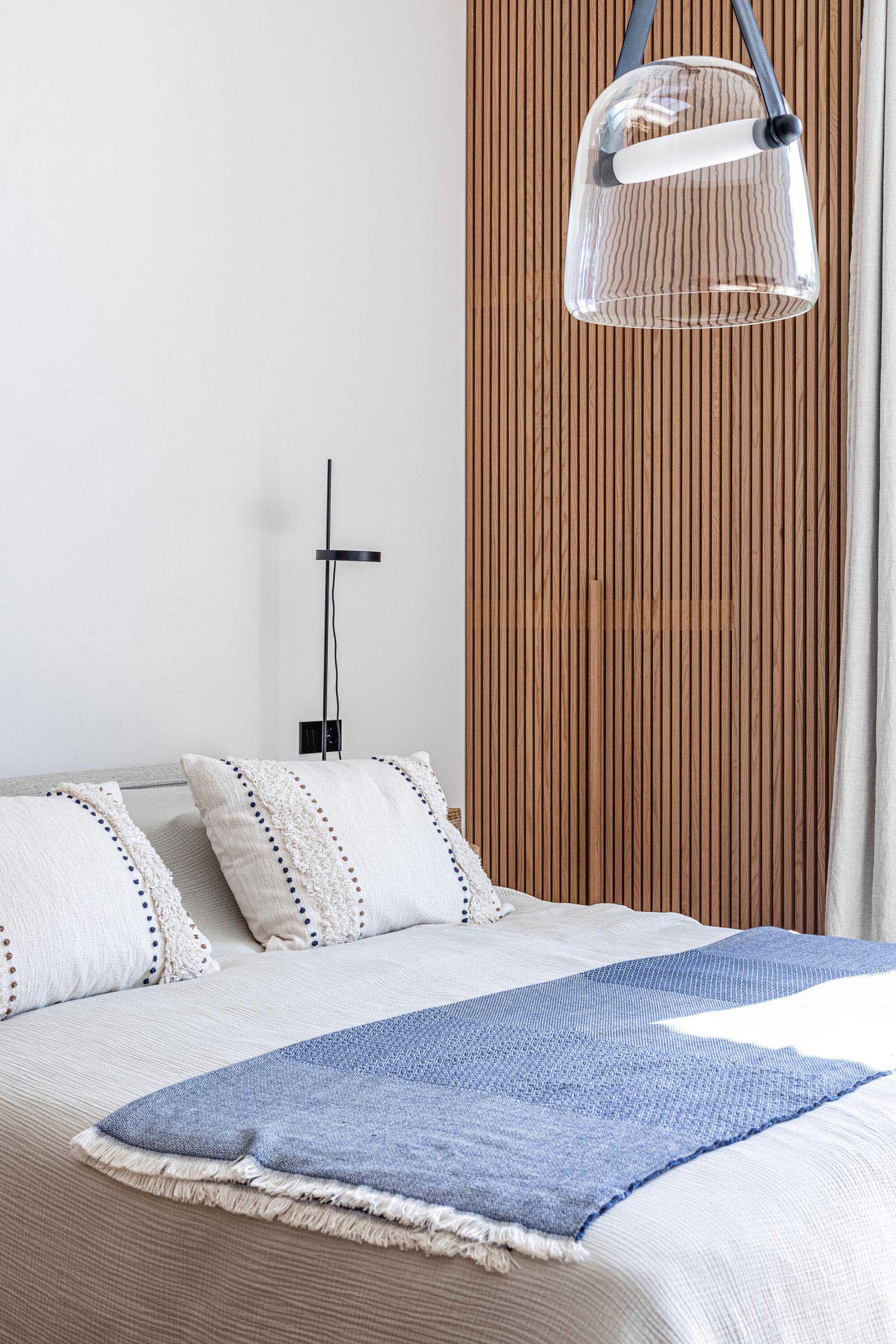 A modern bedroom with a wood slat accent that hides a closet.