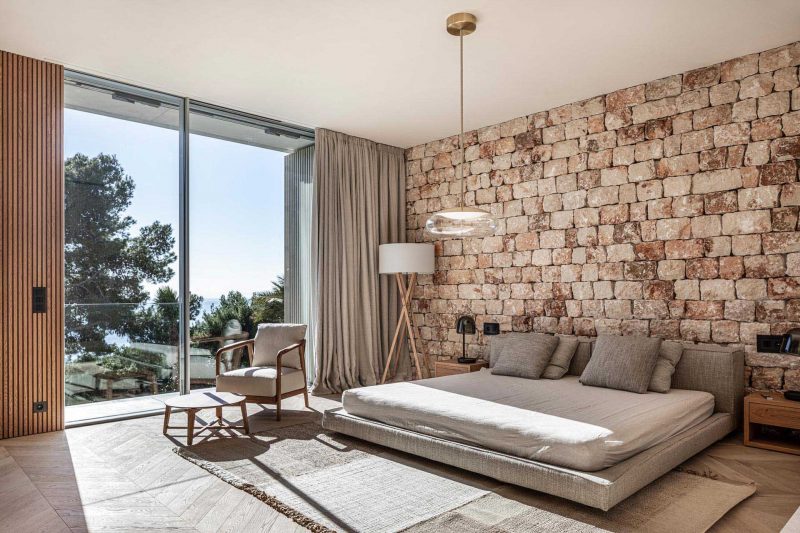 A modern bedroom with a stone accent wall.