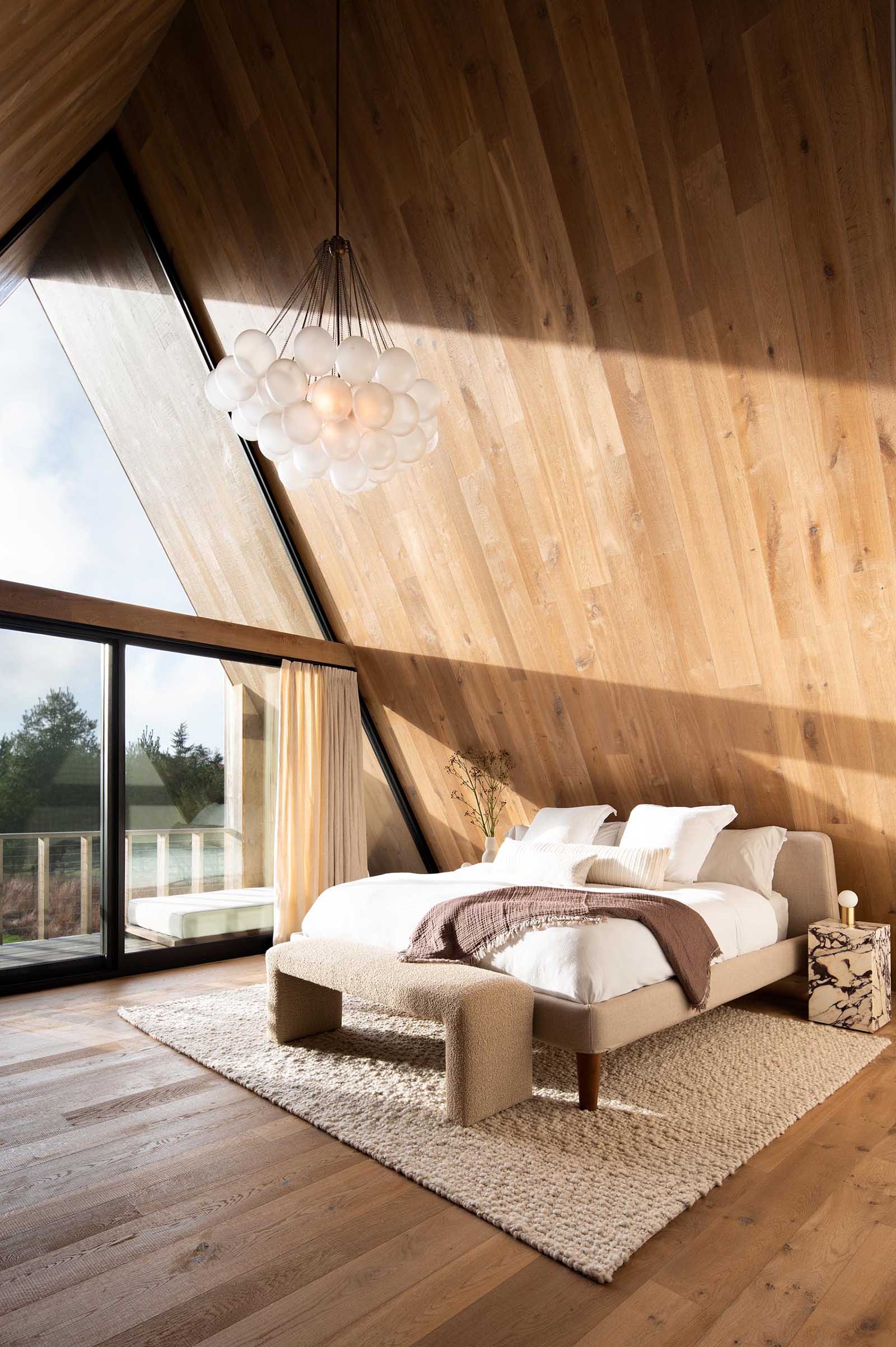 In this modern main bedroom, the steep roof pitch allows for ample natural light to flood the room.