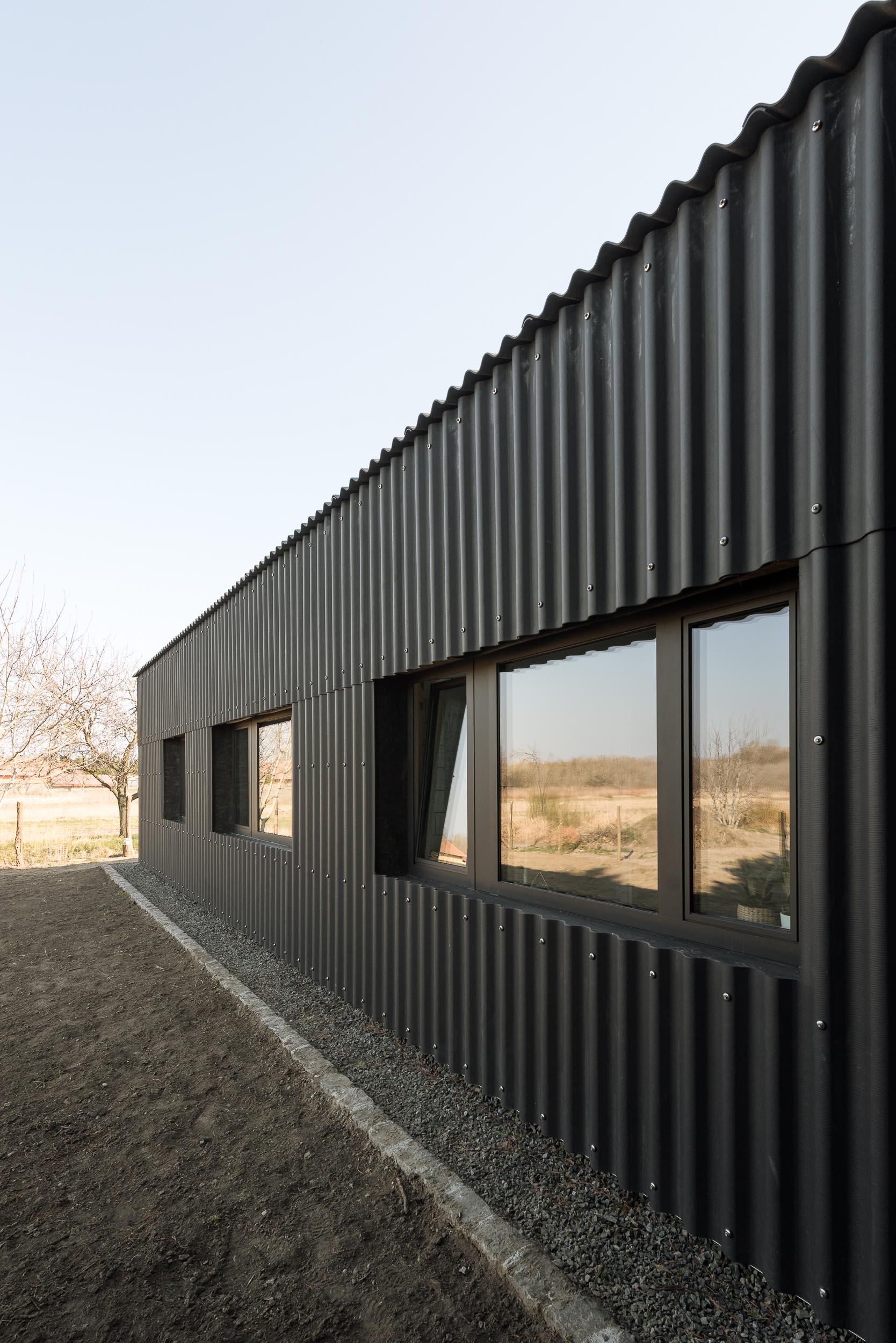 A modern black house with corrugated fibre-cement slate siding and black window frames.