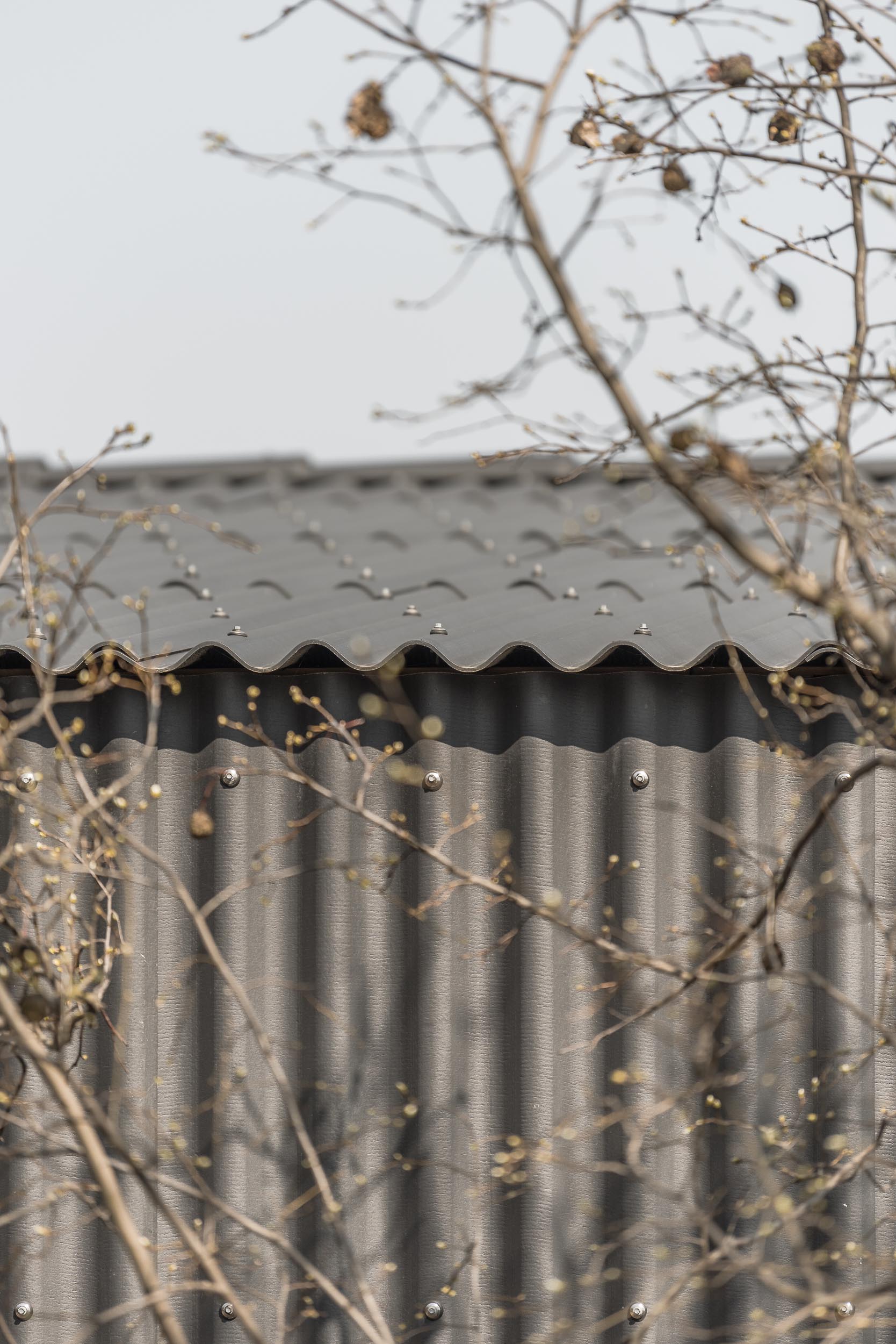 A modern black house with corrugated fibre-cement slate siding.