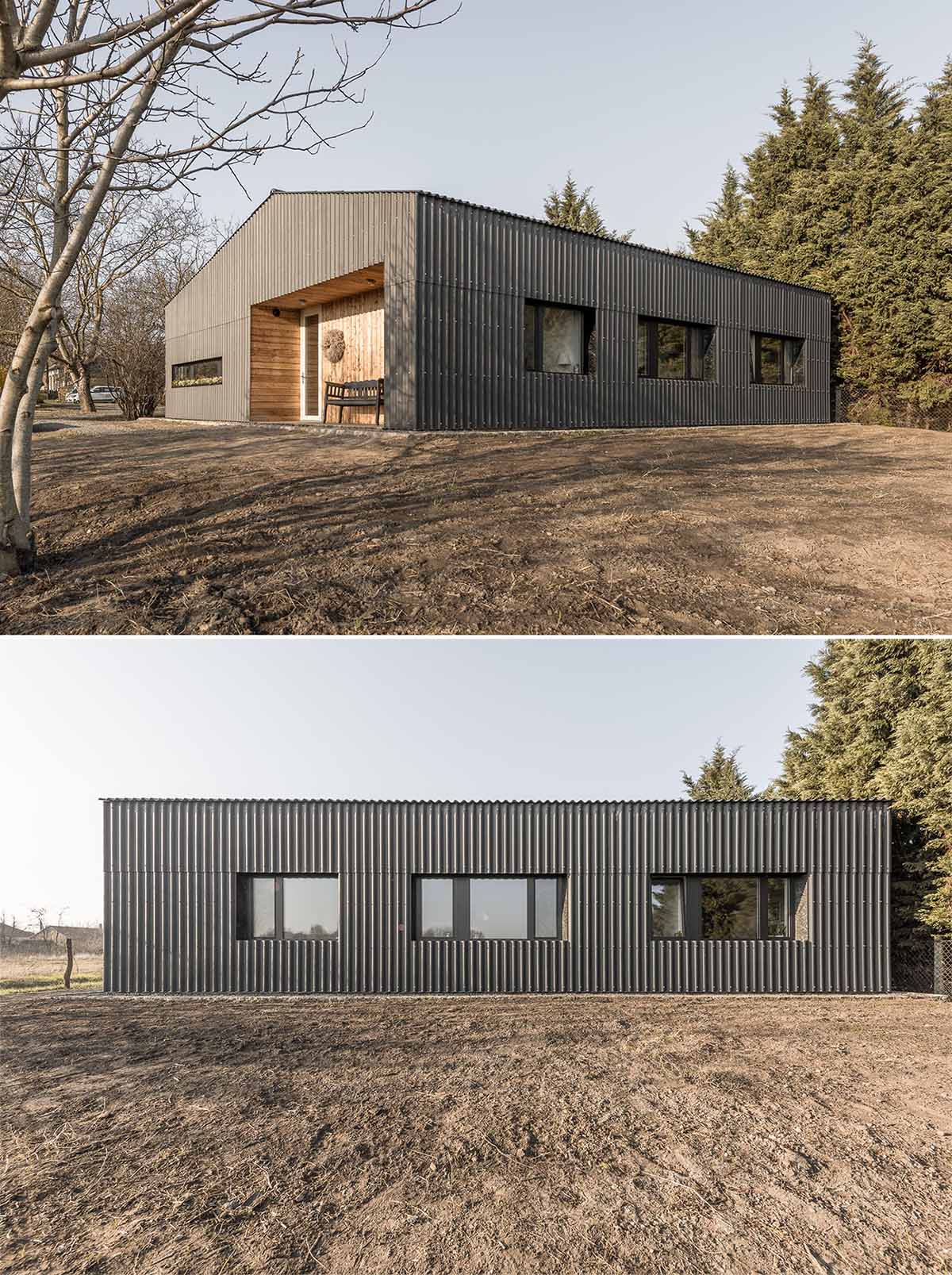 A modern black house with corrugated fibre-cement slate siding, black window frames, and wood lined alcoves.