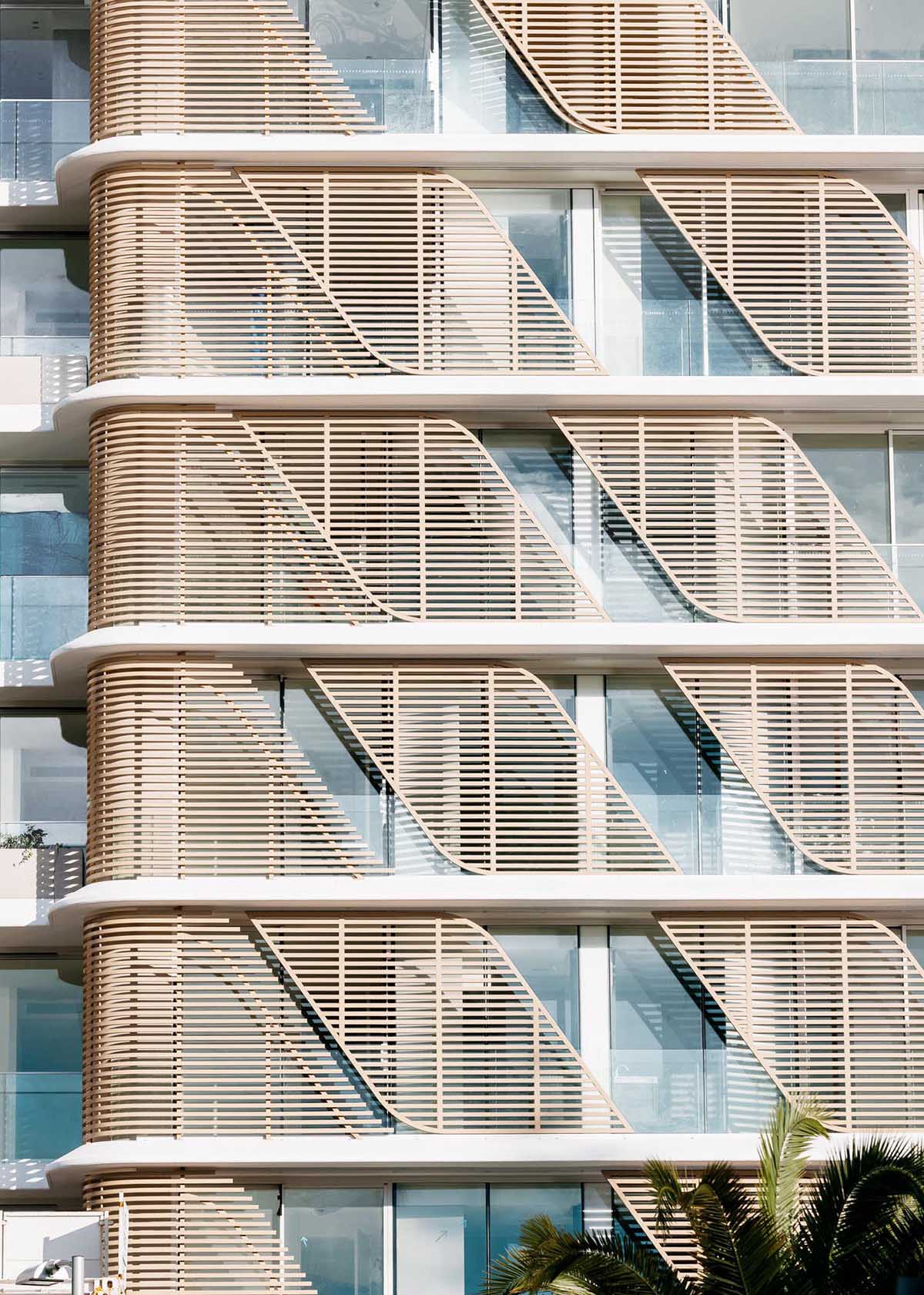 A modern and sculptural building with sliding wood slat screens on the exterior.