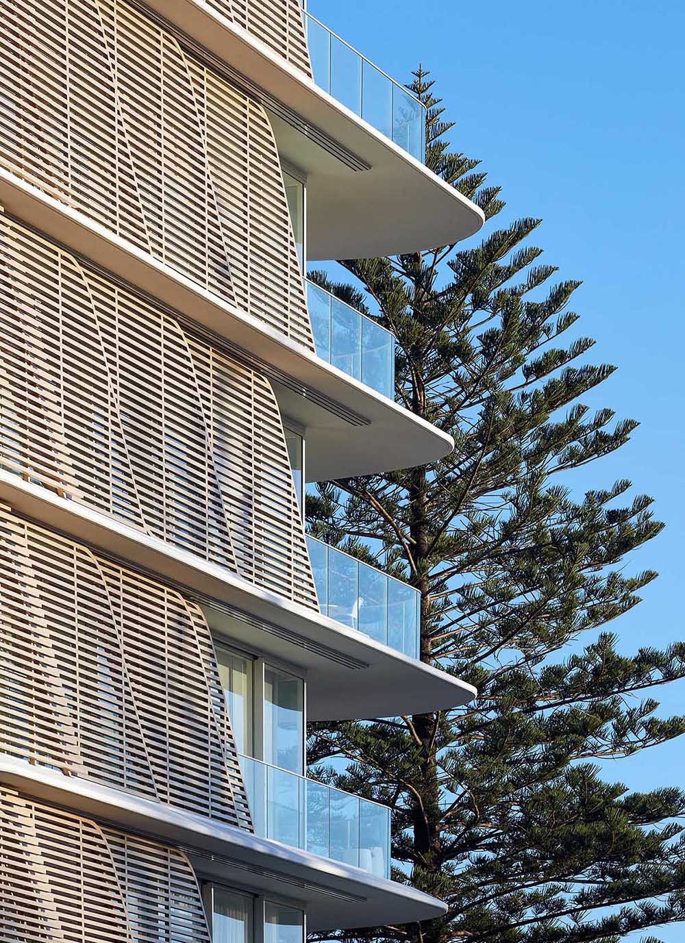 A modern and sculptural building with sliding wood slat screens on the exterior.