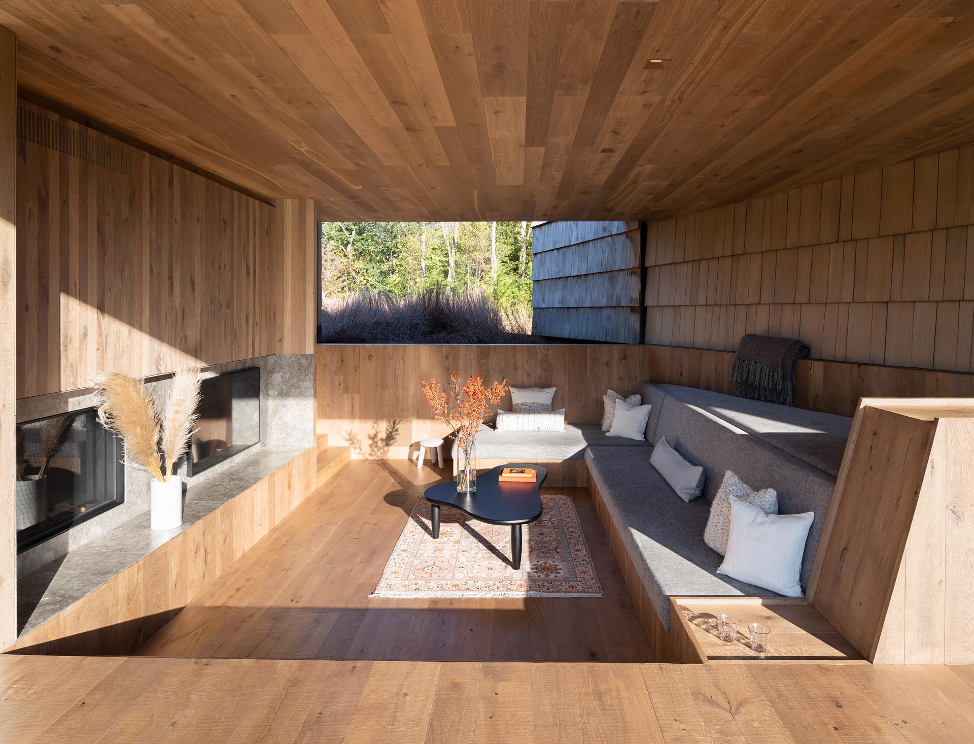 A covered outdoor lounge with a built-in sofa and fireplace.