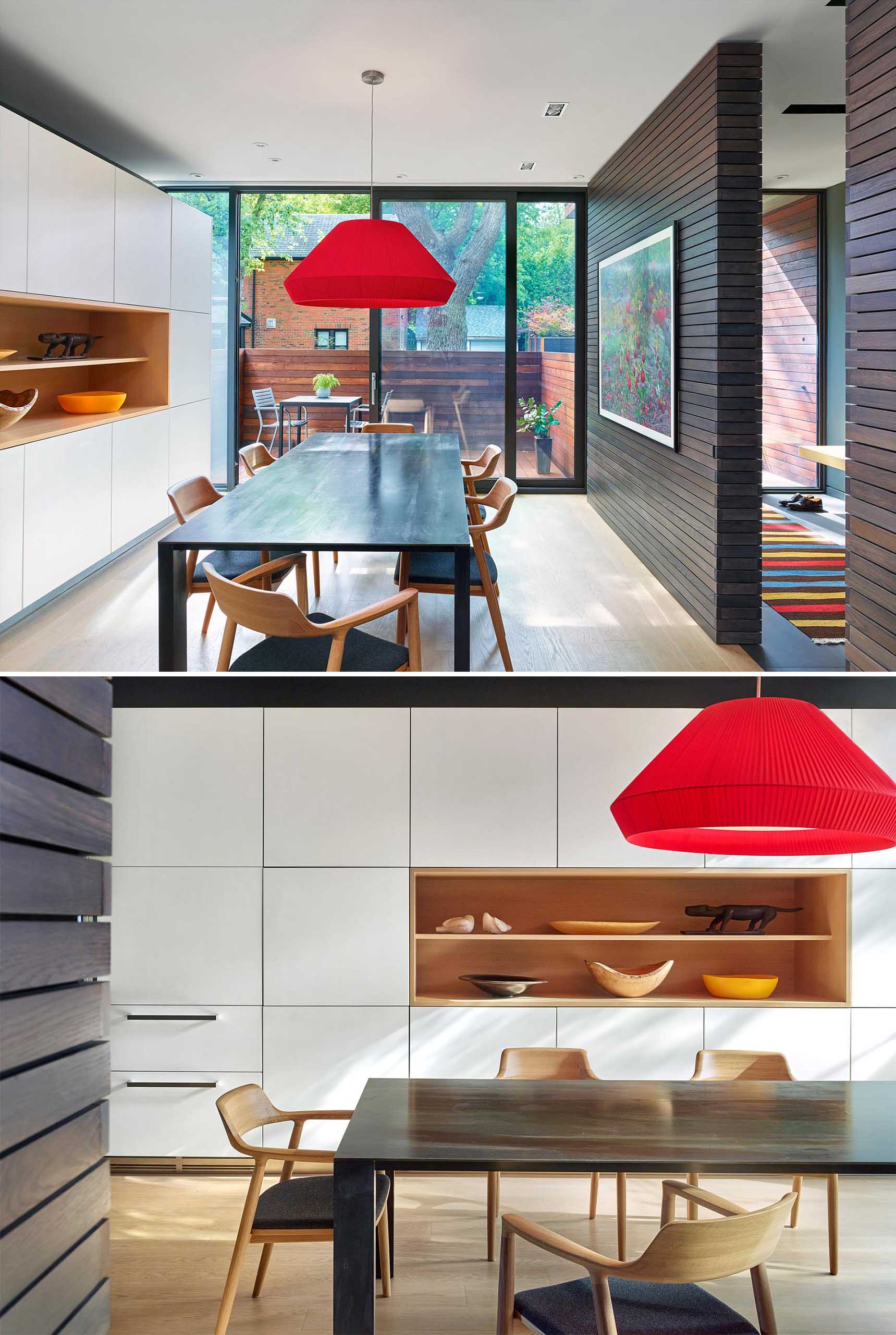 This modern dining room has a sliding glass door that opens to the private front porch patio, while white cabinets along the wall morph into the kitchen cabinets.