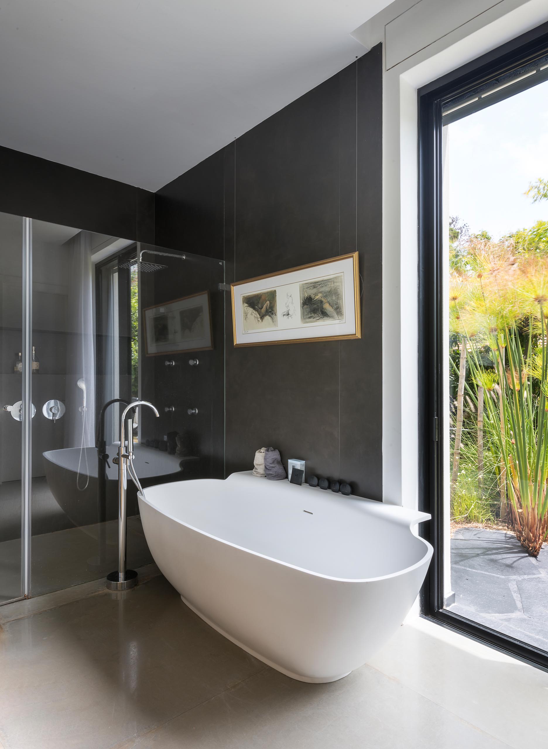 A modern en-suite bathroom with a freestanding bathtub, a black accent wall, and a glass-enclosed shower.