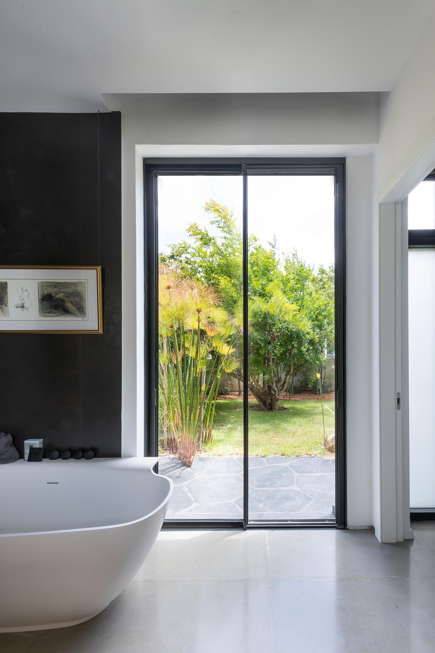 A modern en-suite bathroom with a freestanding bathtub, a black accent wall, and a glass-enclosed shower.