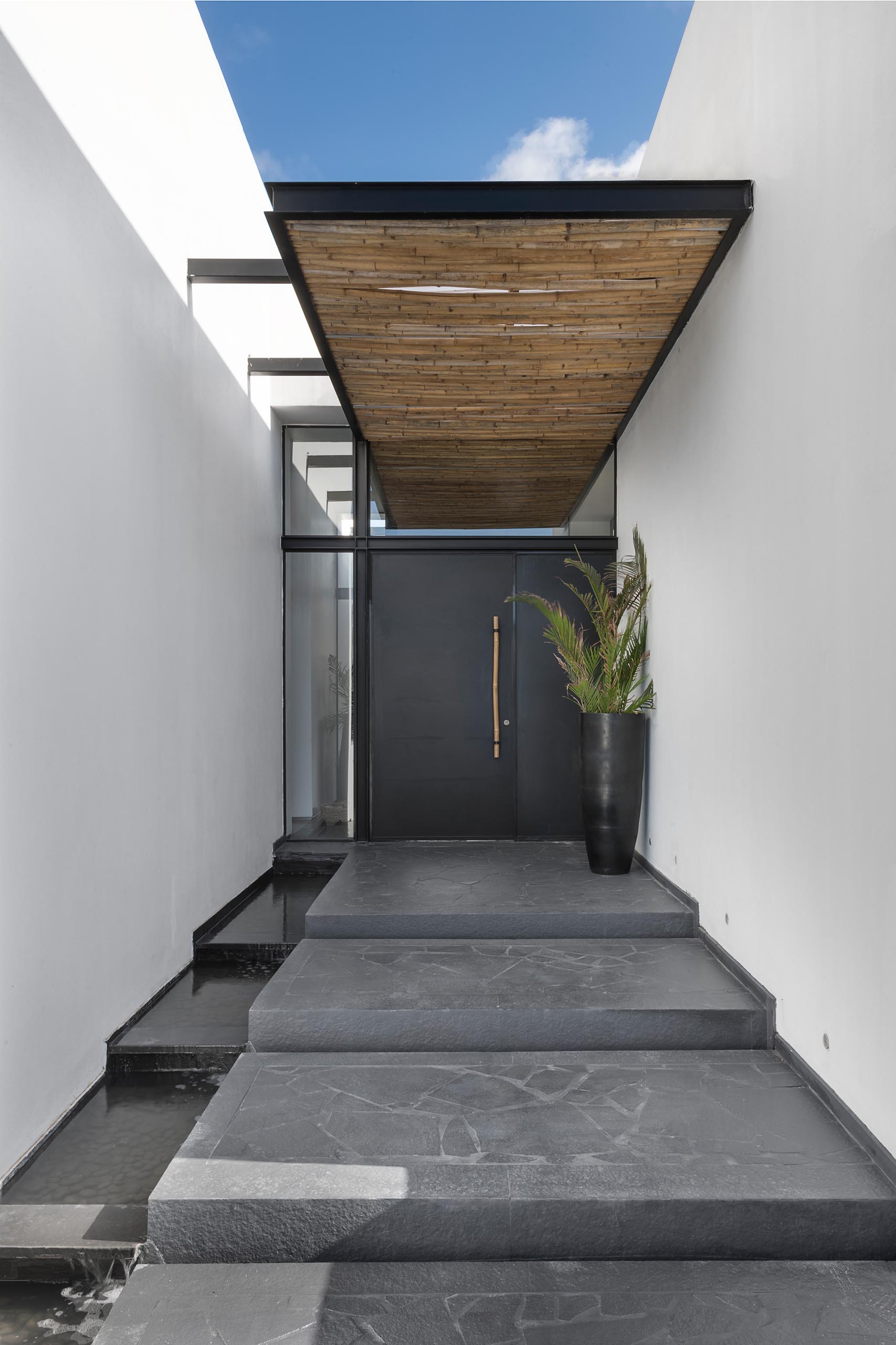 This modern bamboo screens act as a rain cover for the black front door, and flow through to the interior of the home, and then onto the backyard.