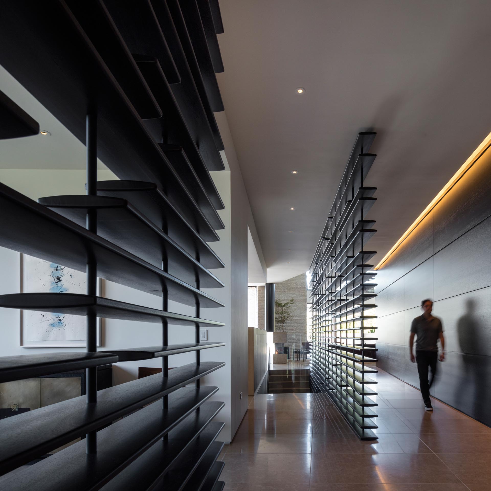 Black partitions and hidden lighting add interest to a hallway that connects the various areas of the home.