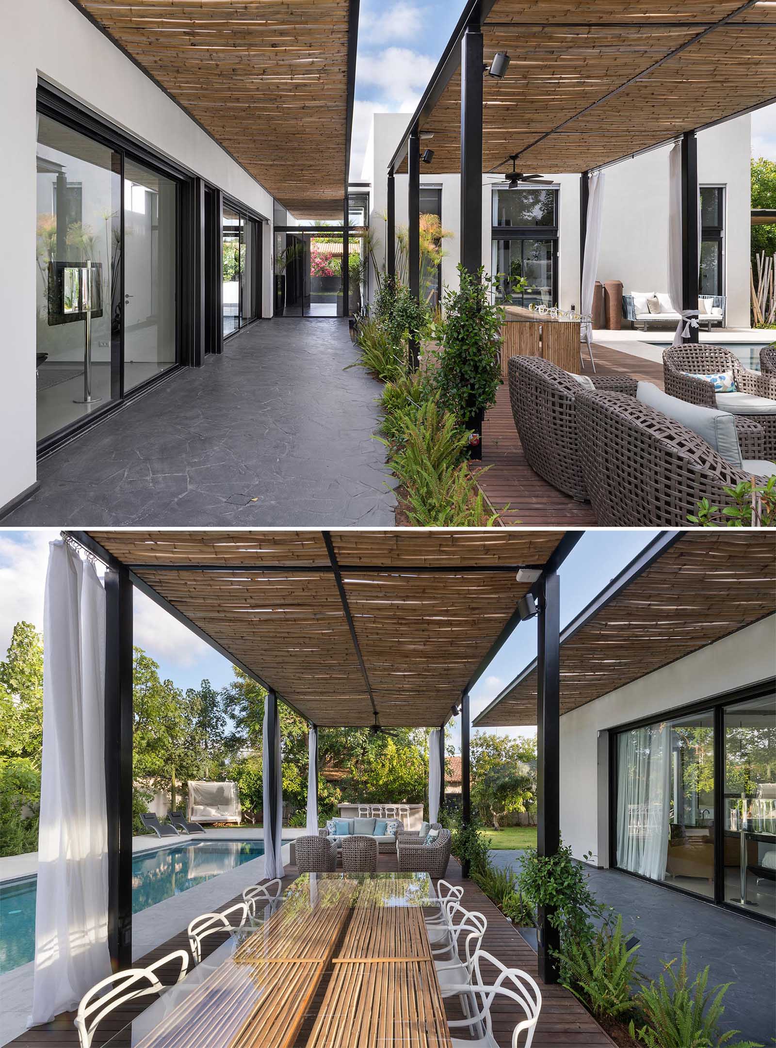 A modern house with a bamboo pergola that shades a pathway and an outdoor living and dining area.