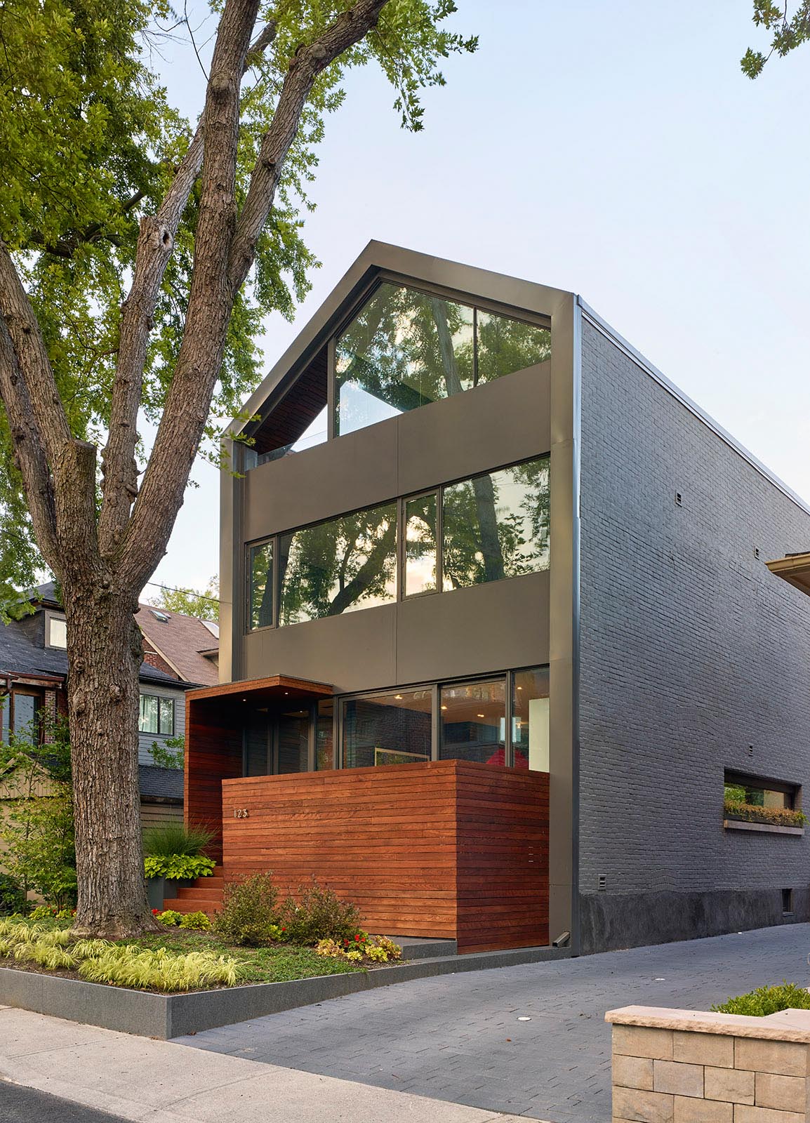 This modern house facade comprises of a combination of windows, doors and spandrel panels, with the windows framing the views to the exterior, bringing natural light and the experience of the changing seasons into the interior.