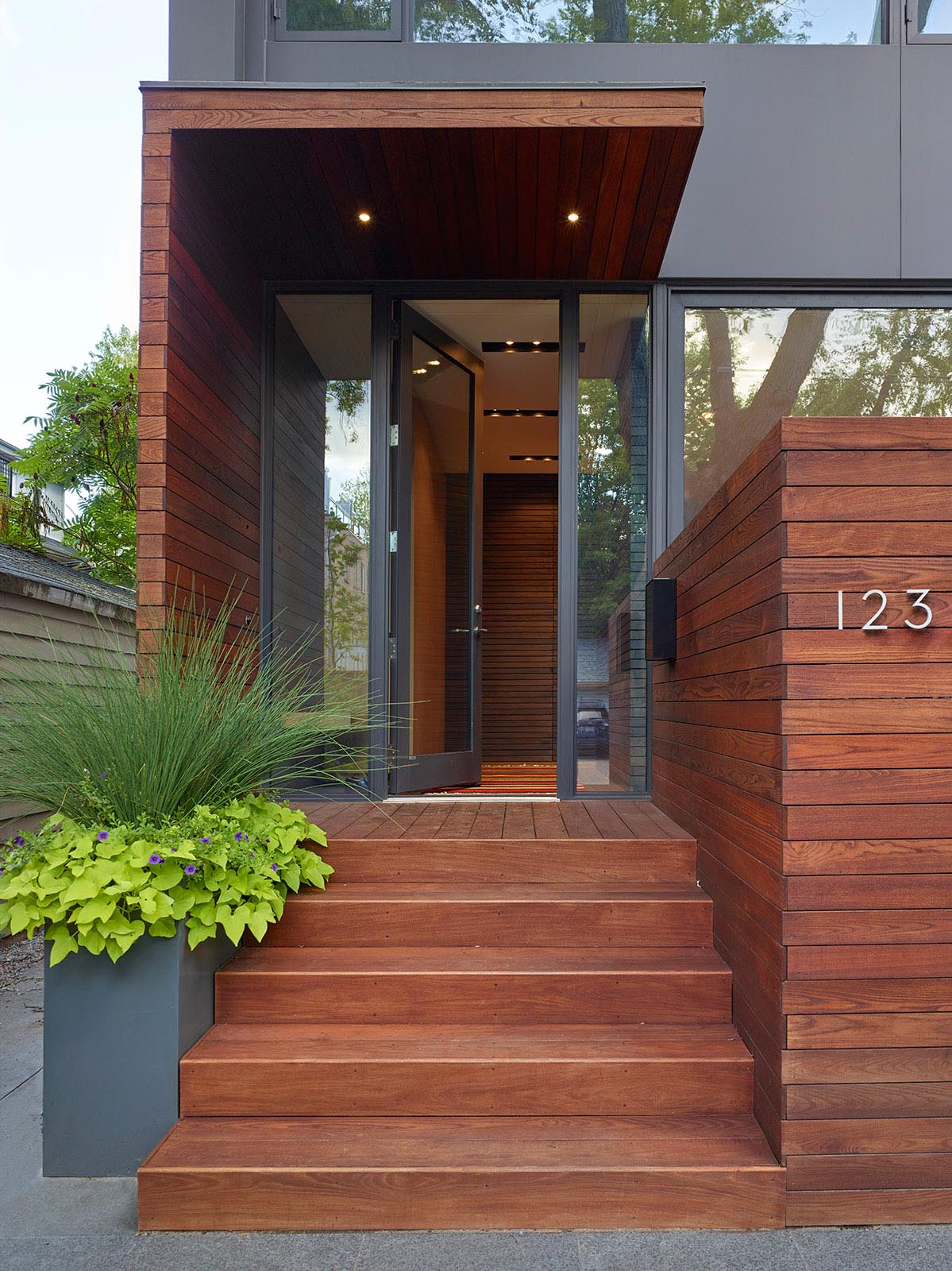 The porch beside the front door acts as a private outdoor dining room enclosed by a five-foot-high wood screen, extending the private realm into the public arena.